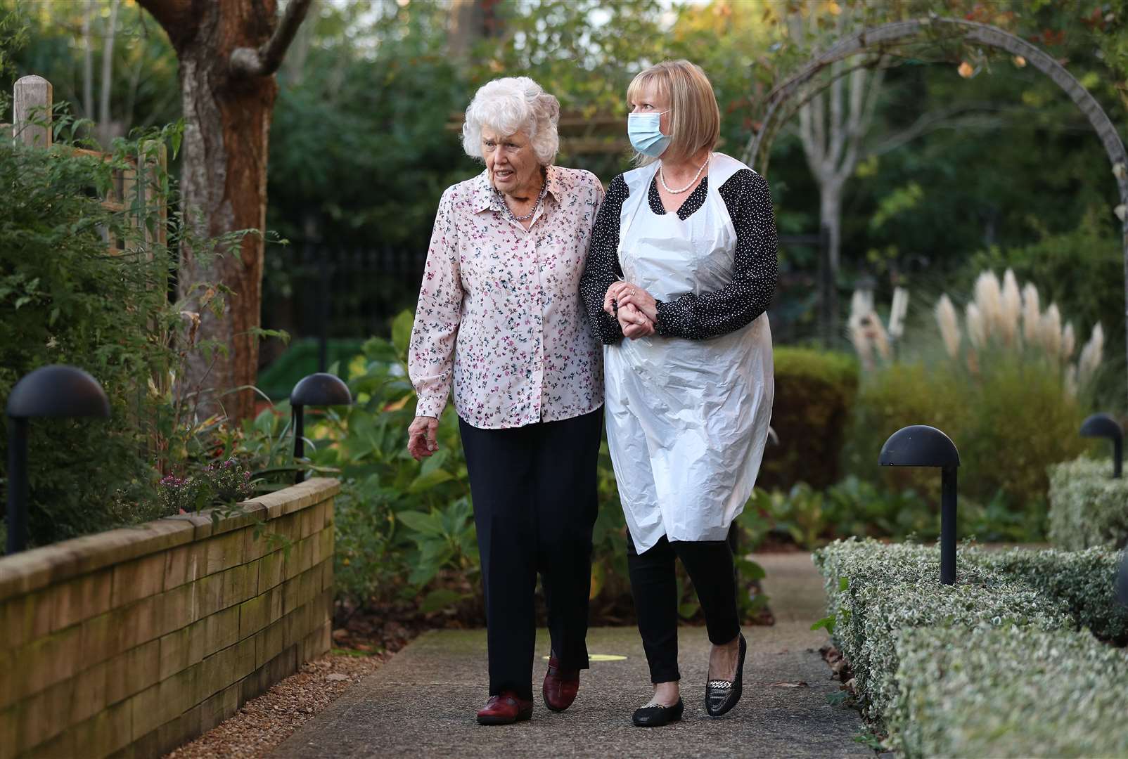 Sandy helps her mother Doreen walk around the grounds of Sunrise of Bassett care home in Southampton (Andrew Matthews/PA)