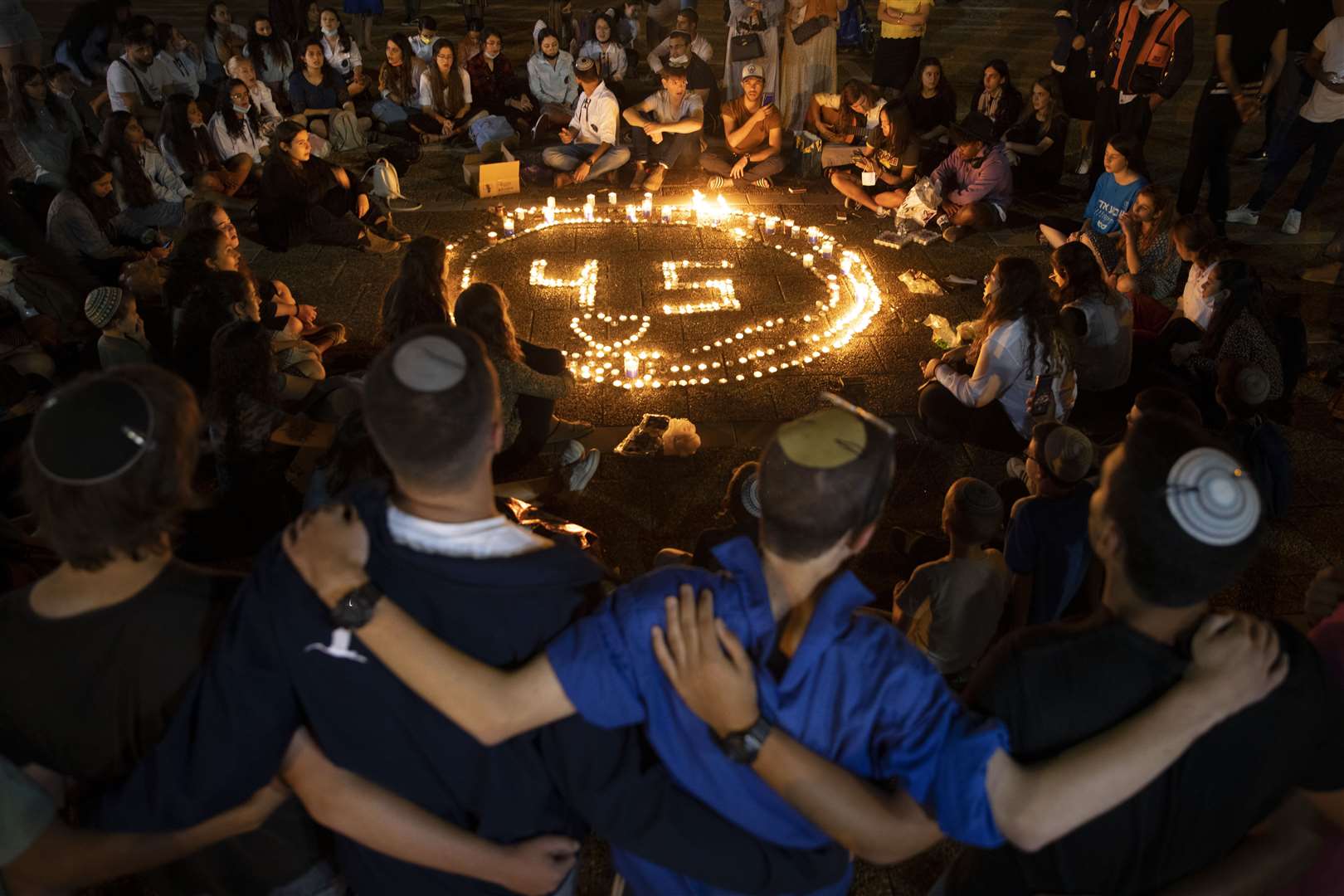 People gather around candles during a vigil in Tel Aviv in memory of the 45 ultra-Orthodox Jews killed in a stampede at a religious festival in northern Israel (Oded Balilty/AP)