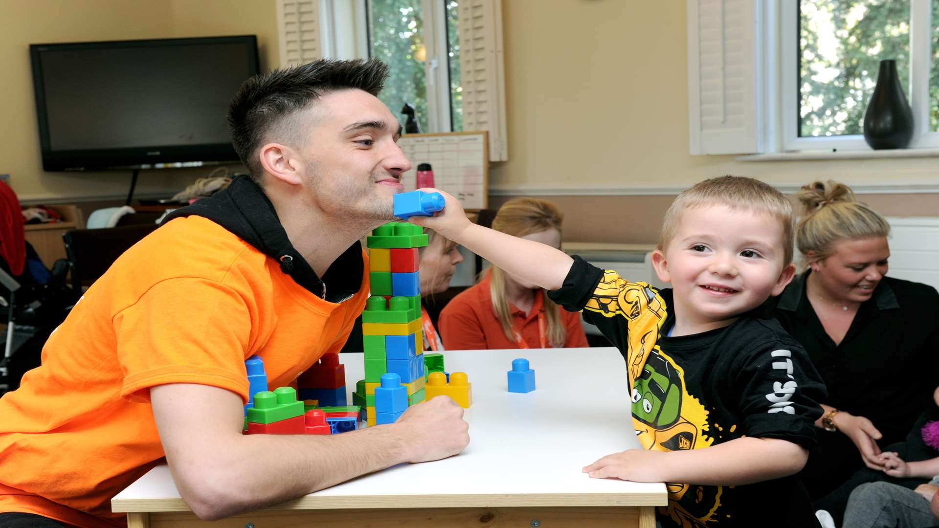 Tom Parker, from The Wanted, has fun with a young boy supported by hospice charity ellenor