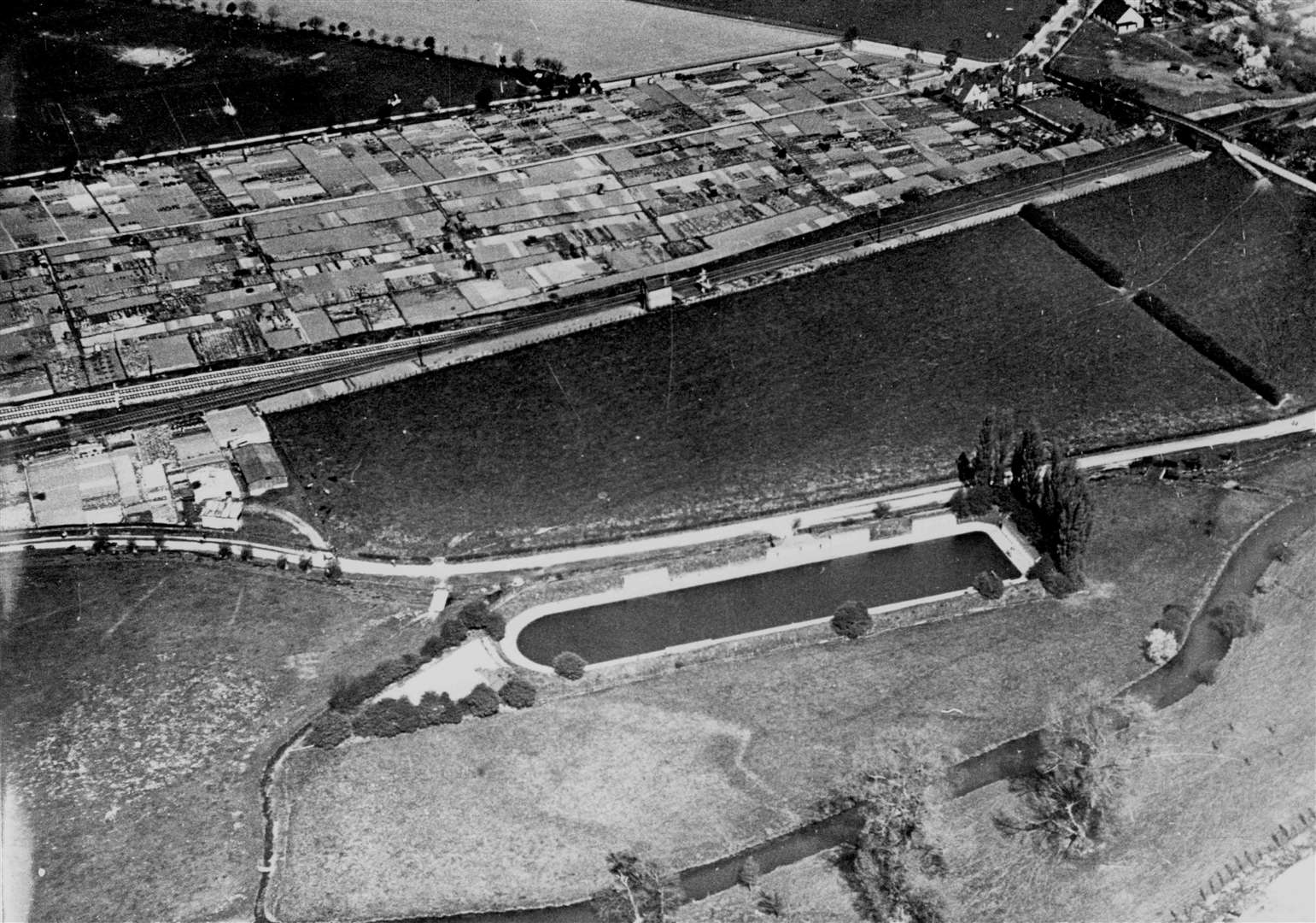 The old outdoor swimming baths off Whitehall Road, Canterbury, were built by the side of the Stour in 1876 - in the Toddlers Cove area. Measuring 375ft, the pool was of great size. Swimming was banned on health grounds during the war and the pool was later used for boating. As late as 1966 the council was still hoping to reopen the baths, despite its plans for the £277,000 pool at Kingsmead, which opened in 1970. Rheims Way of the early 1960s was to come between Victoria recreation ground (top left) and the houses at the end of Queens Avenue (towards the top right). Picture: 'Images of Canterbury' book