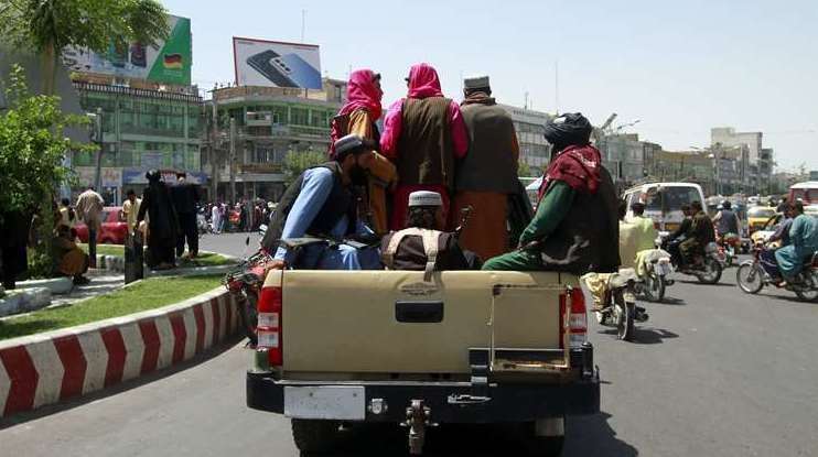 Taliban fighters sit on the back of a vehicle in the city of Herat, west of Kabul (Hamed Sarfarazi/AP)