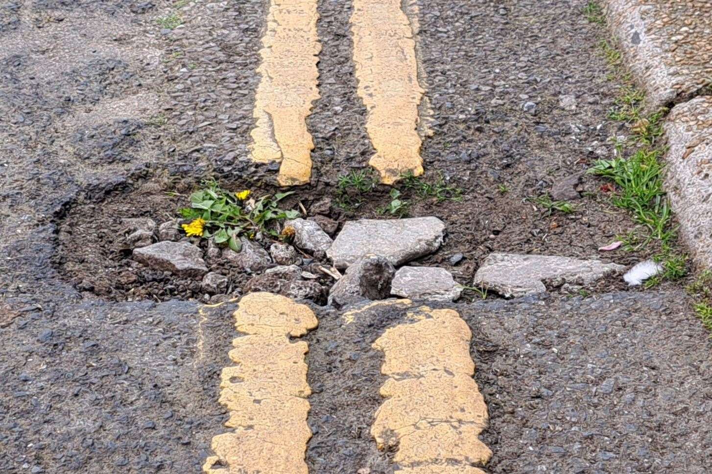 The holes in the roads are in various sizes and depths. Someone has tried to fill this one wth stones