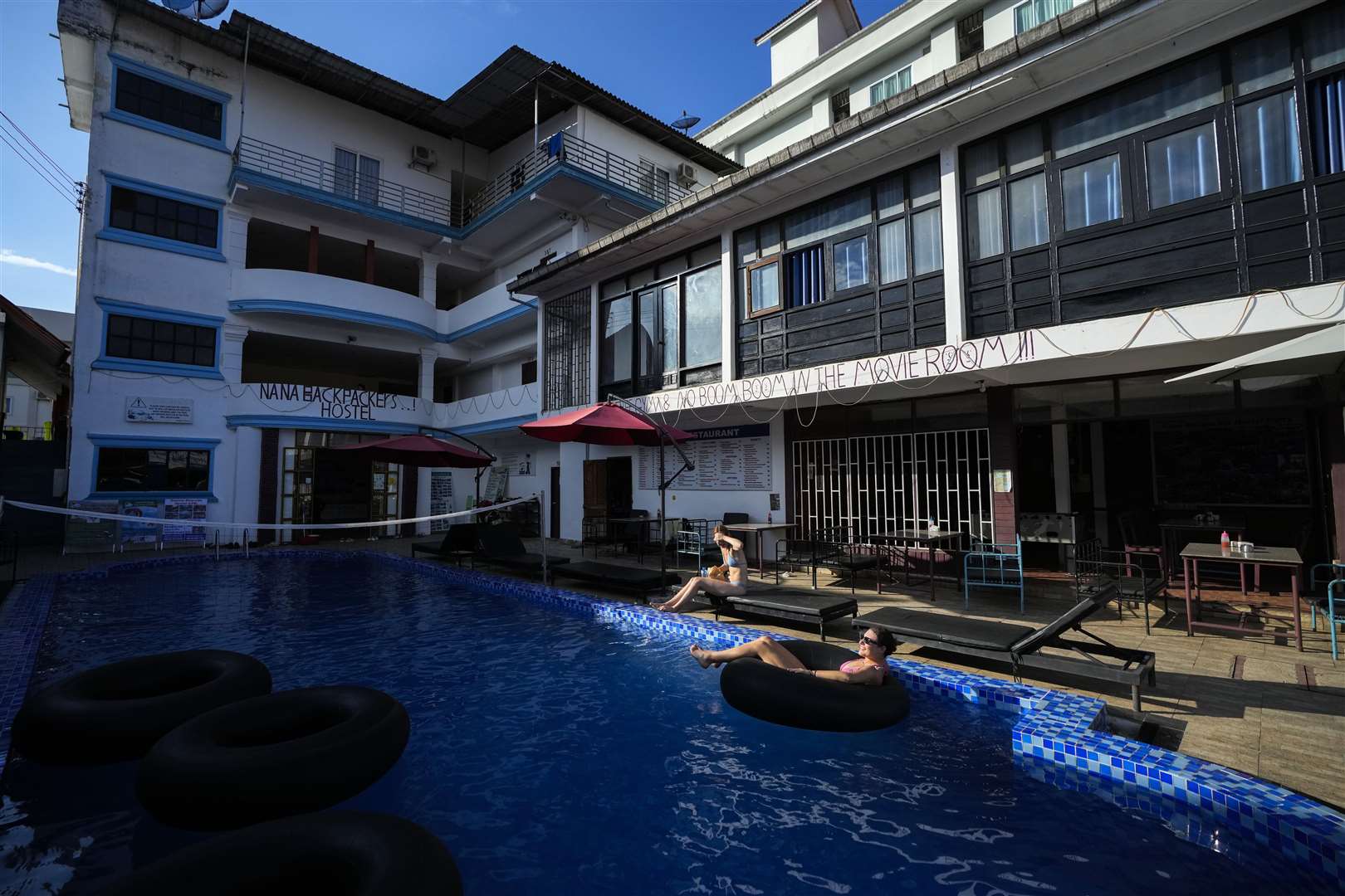 Foreign tourists relax at a swimming pool at Nana Backpack hostel in Vang Vieng, Laos (Anupam Nath/AP)