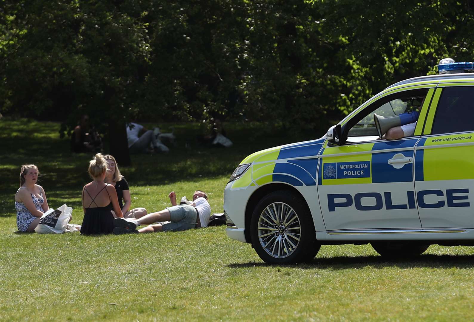 Police officers in a patrol car move sunbathers on in Greenwich Park, London, during lockdown (Yui Mok/PA)