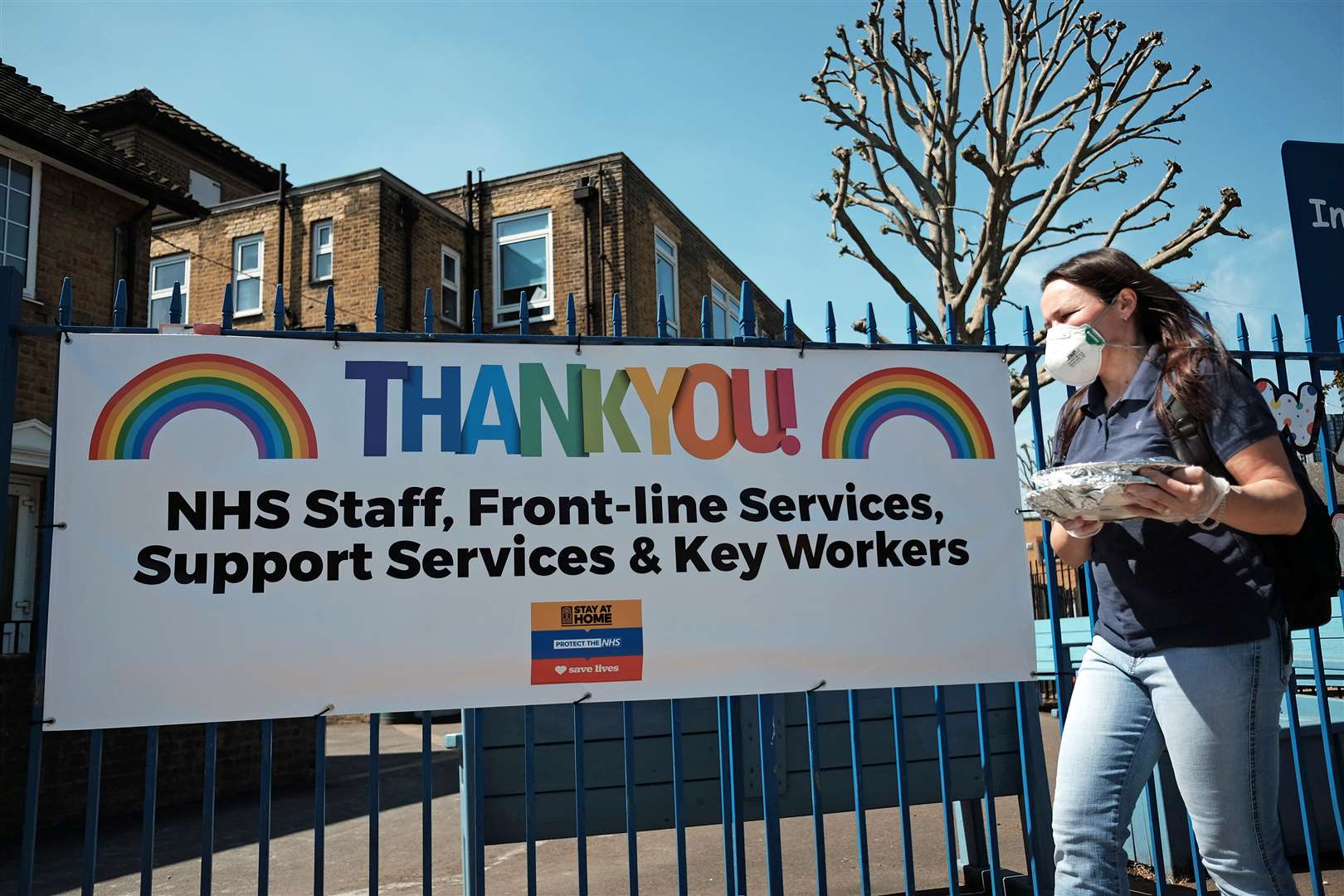 A woman wearing a face mask walking past a ‘Thank You’ to NHS staff and key workers banner on the Isle of Dogs, east London. (Yui Mok/PA)