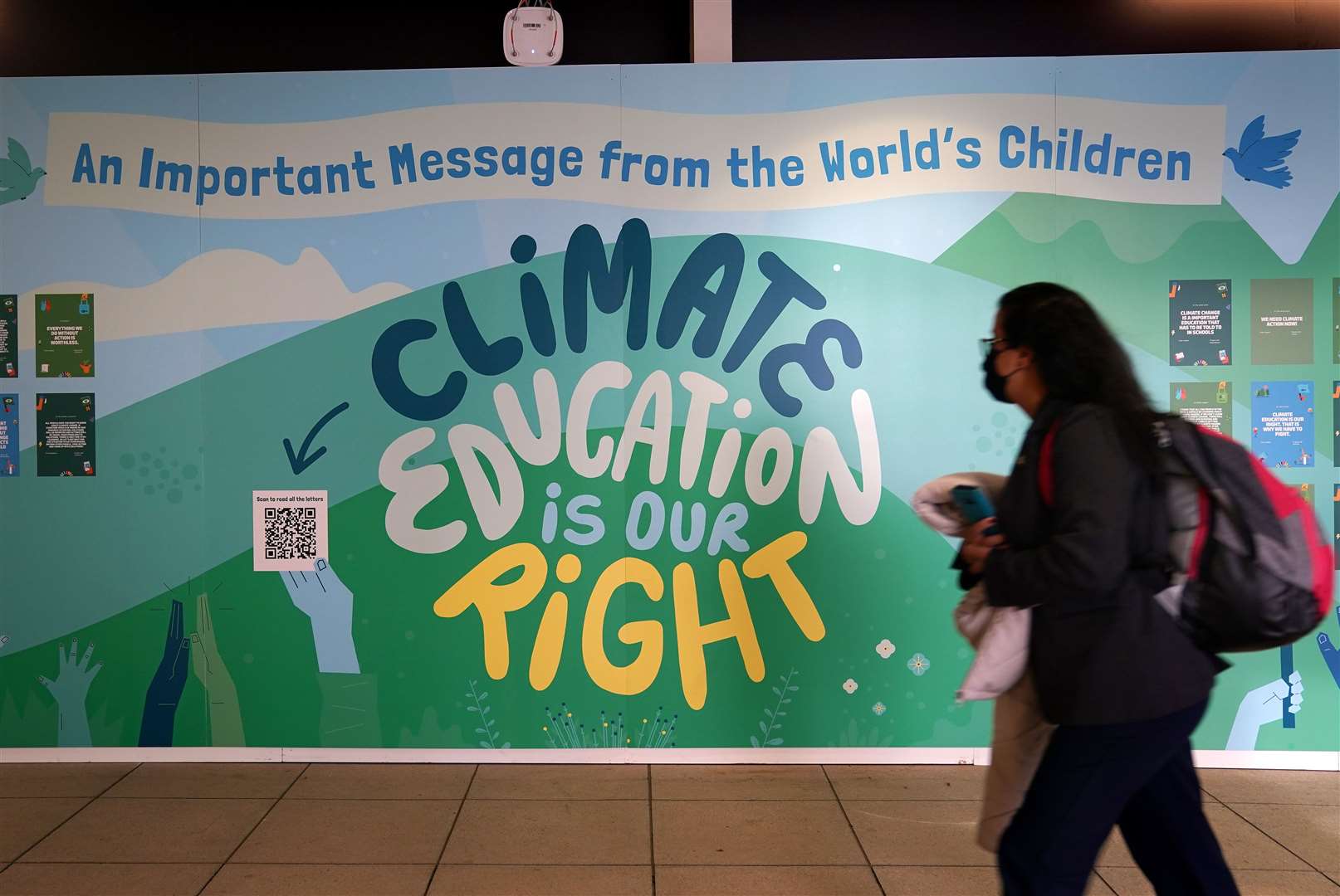 A delegate walks passed a message on a wall in the Scottish Event Campus at the start of the Cop26 summit (Andrew Milligan/PA)