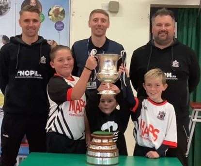 Sandown School pupils, pictured with Deal Town’s Tom and Ben Chapman, and manager Steve King, get their hands on the Southern Counties East League Premier Division trophy