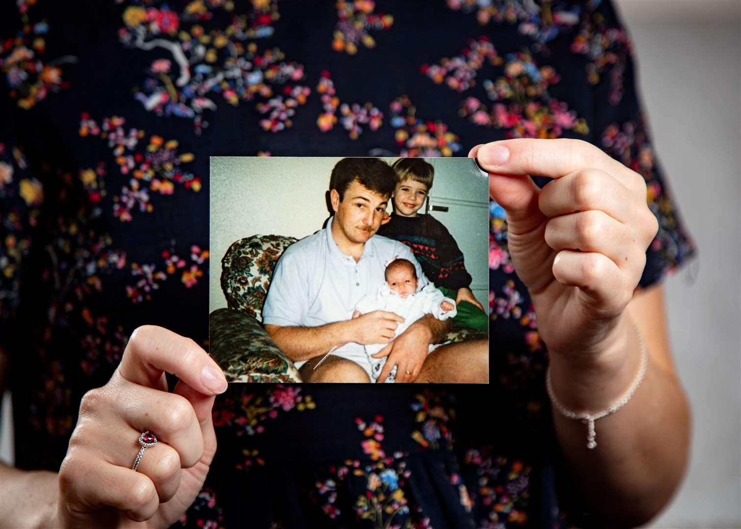 Stephanie holding up a photo of her as a baby being held by Mark, who would have been 27 at the time. Picture: SWNS