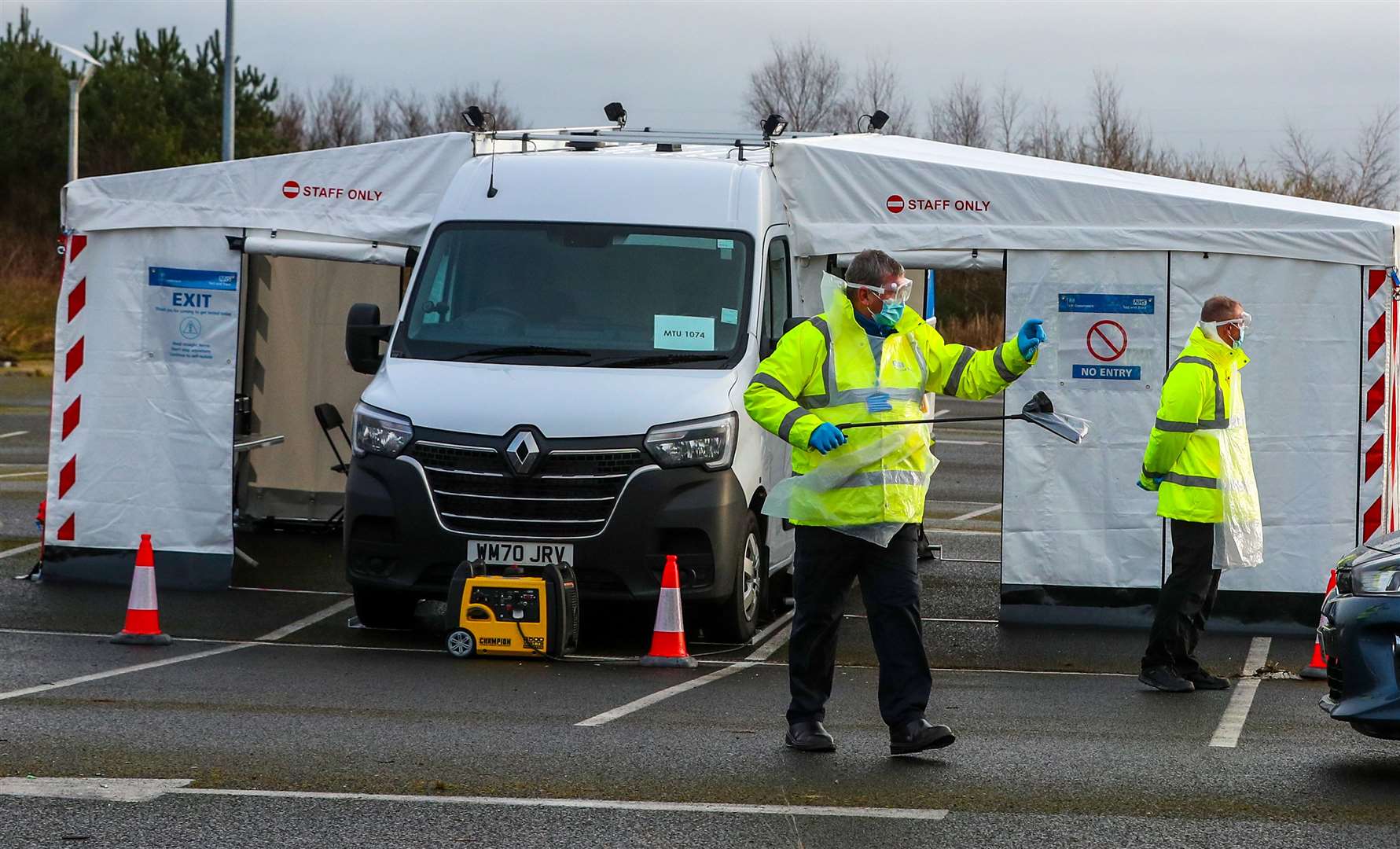 An NHS Test and Trace worker carries a test kit in a drive-through testing centre in Southport, Lancashire (Peter Byrne/PA)