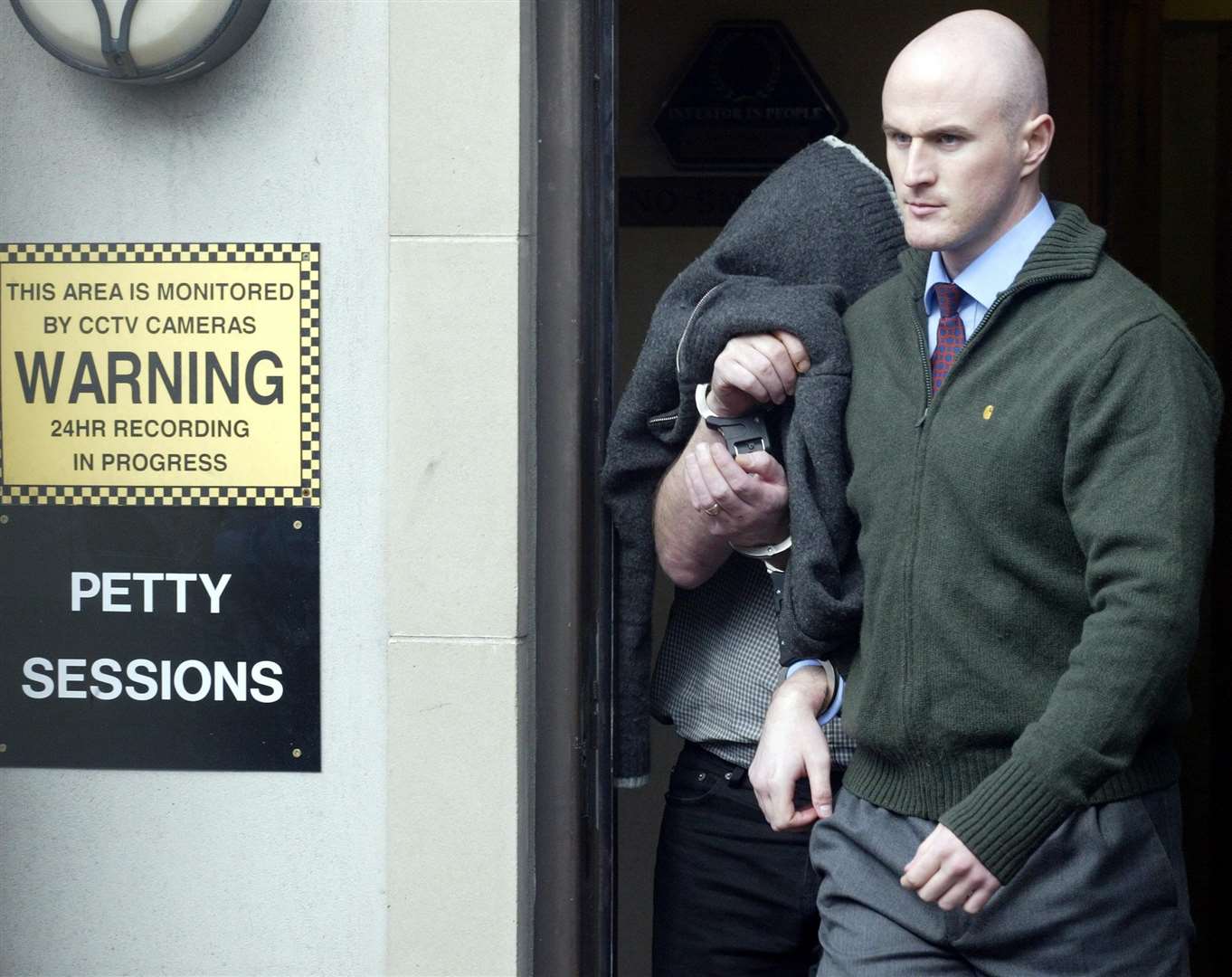 Cyril McGuinness (left, head covered) being led away from a court in Northern Ireland in 2005 (Paul Faith/PA)