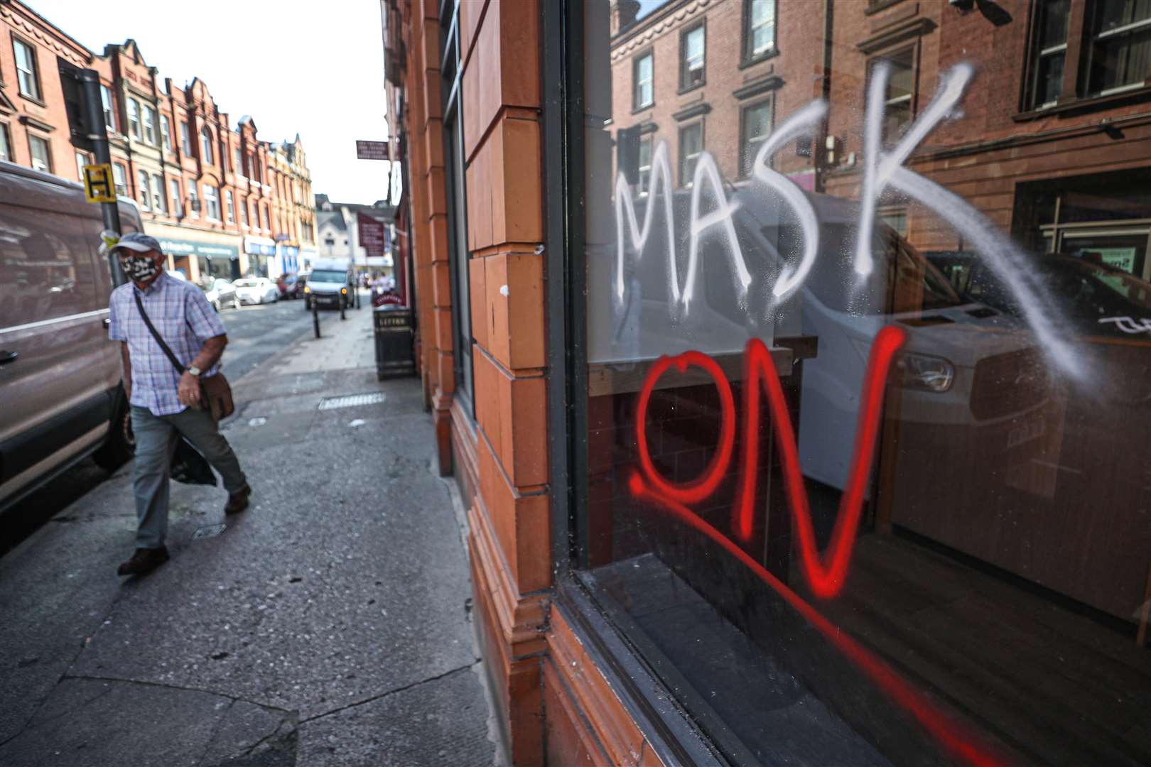 A man wearing a face covering walks past graffiti with the slogan Mask On covering a vacant shop window in the High Street in Worcester (David Davies/PA)