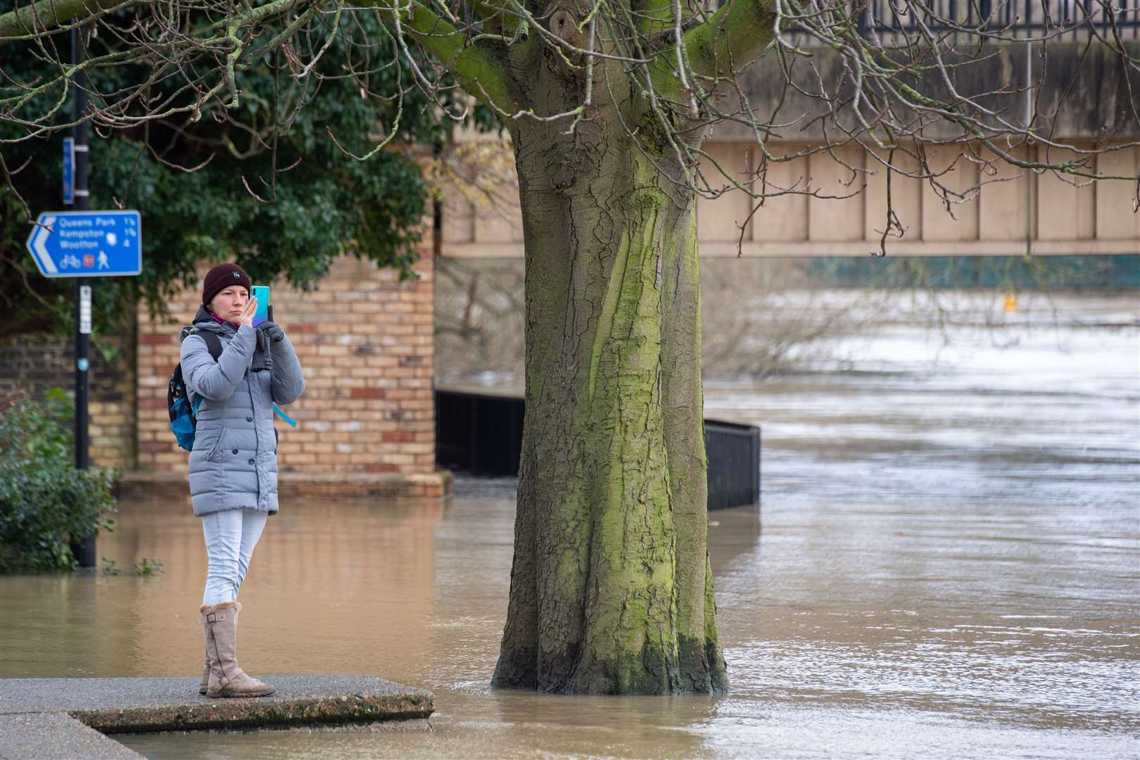 A woman takes a photo of flooding in Bedford (Joe Giddens/PA)