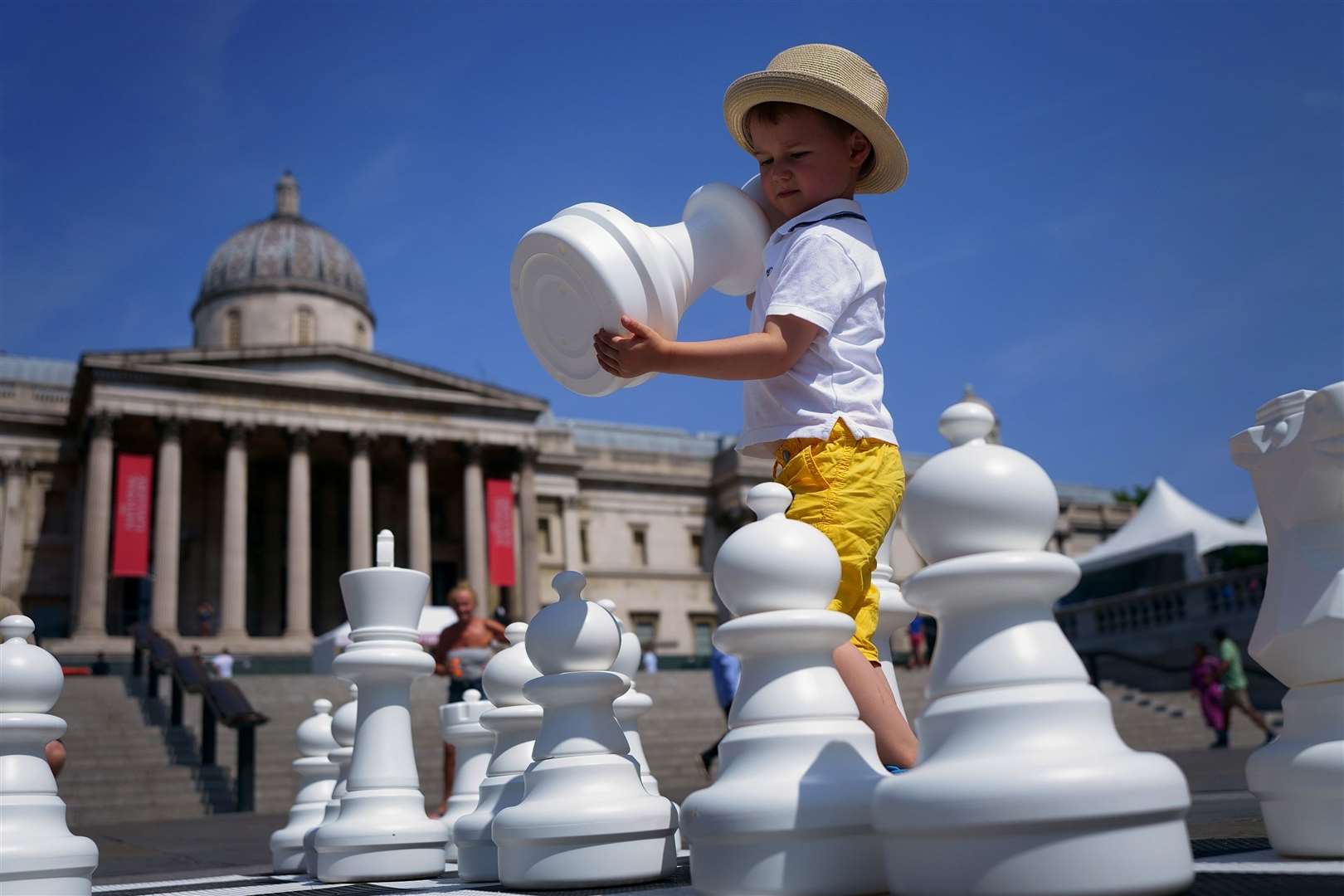 A young boy wearing his sun hat takes part in ChessFest, the UK’s largest one-day chess event, at Trafalgar Square in central London (Victoria Jones/PA)