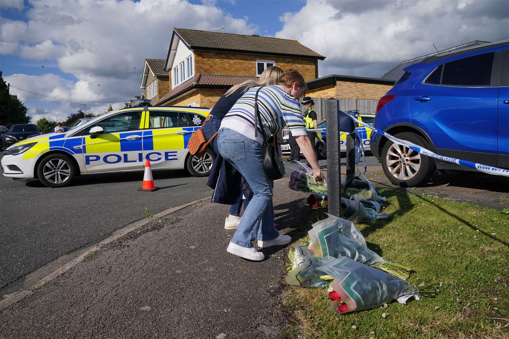 People deliver floral tributes near to the scene in Ashlyn Close, Bushey, Hertfordshire (Jonathan Brady/PA)