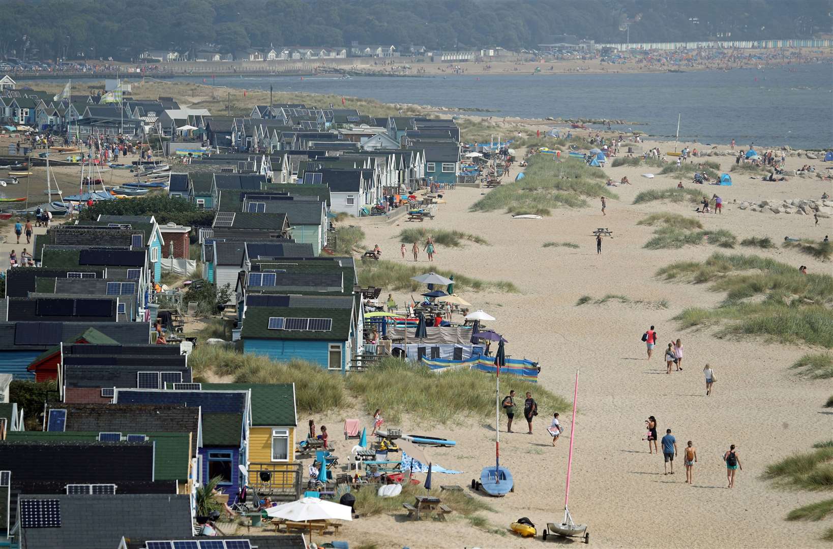 People enjoy the hot weather by beach huts on Mudeford sandbank, Dorset (Andrew Matthews / PA)