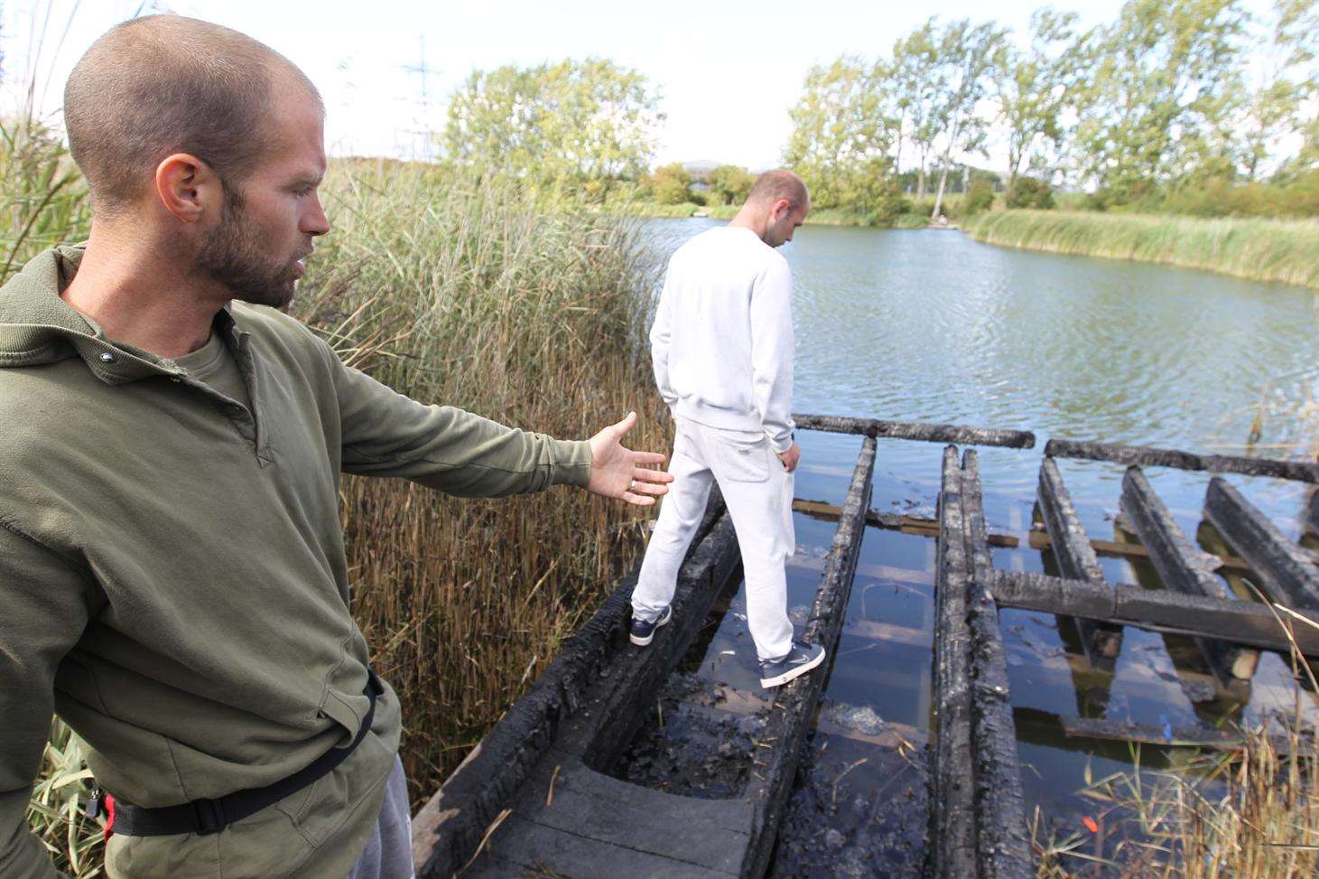 Shaun Fischer and Ryan Butler point out a burnt out jetty at a fishing lake at the back of Milton Creek Country Park