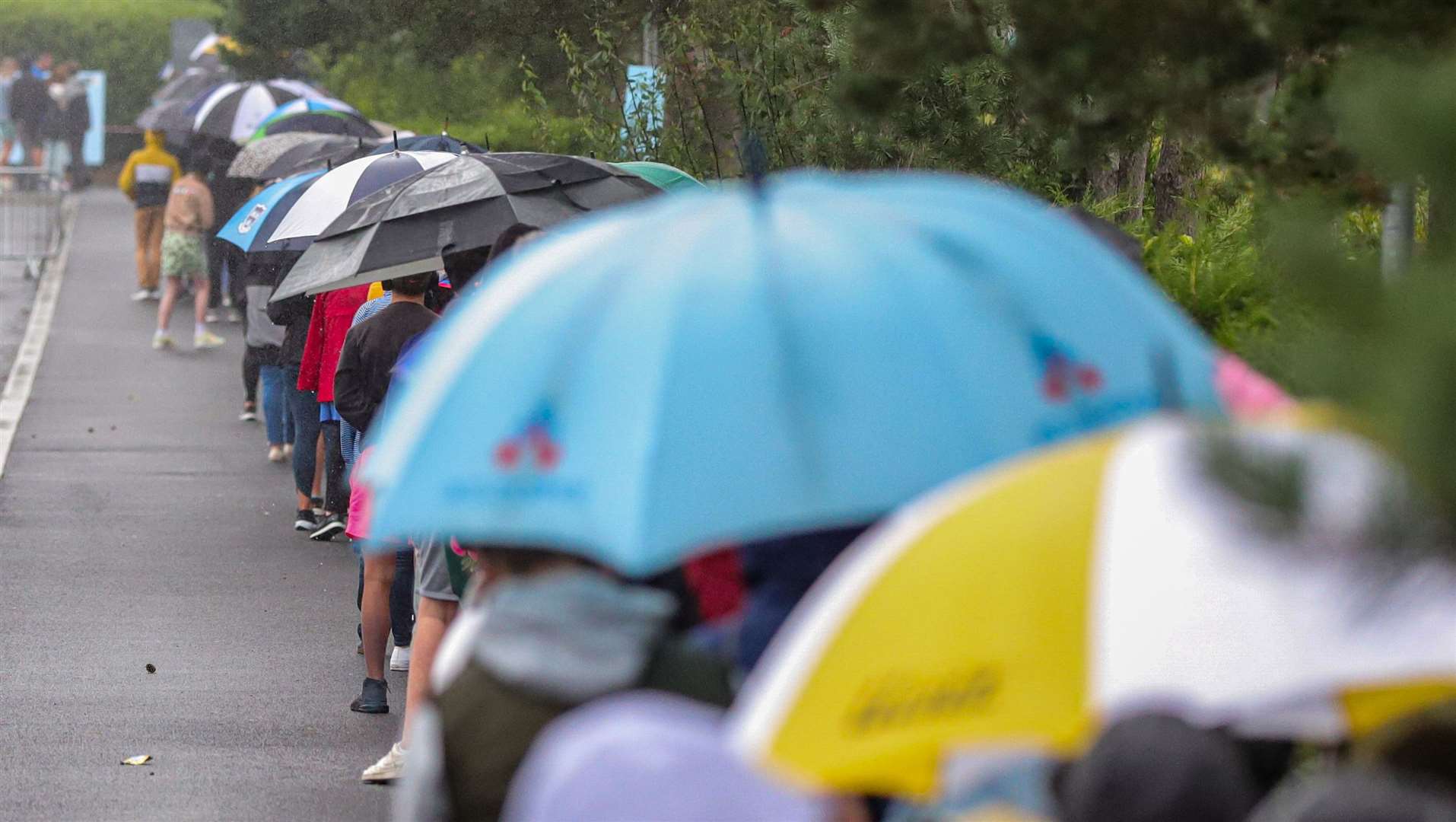 Parents and their children queue in the pouring rain outside the Citywest Covid-19 Vaccination Centre in Dublin on Saturday (Damien Storan/PA)