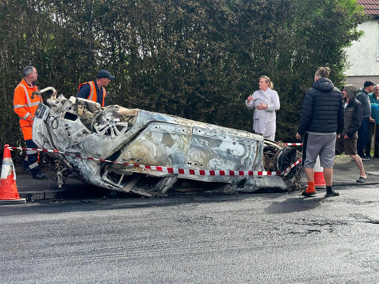 Council workers secure the area immediately around a car that was set alight following the deaths (PA)