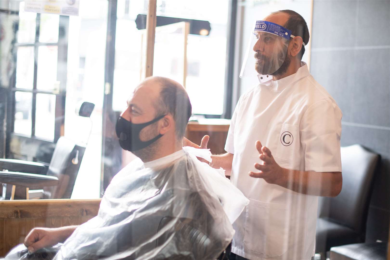 Mehmet Yusuf, owner of Chaplin’s of London Barbers in Brockley, south London, demonstrates the personal protective equipment that will be used on reopening (Dominic Lipinski/PA)