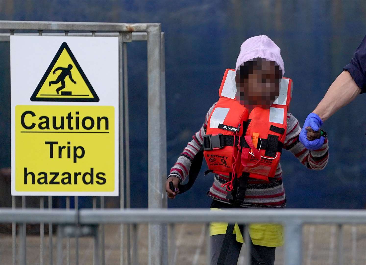 A young girl is escorted by a Border Force officer as a group of people thought to be migrants are brought in to Dover (PA)