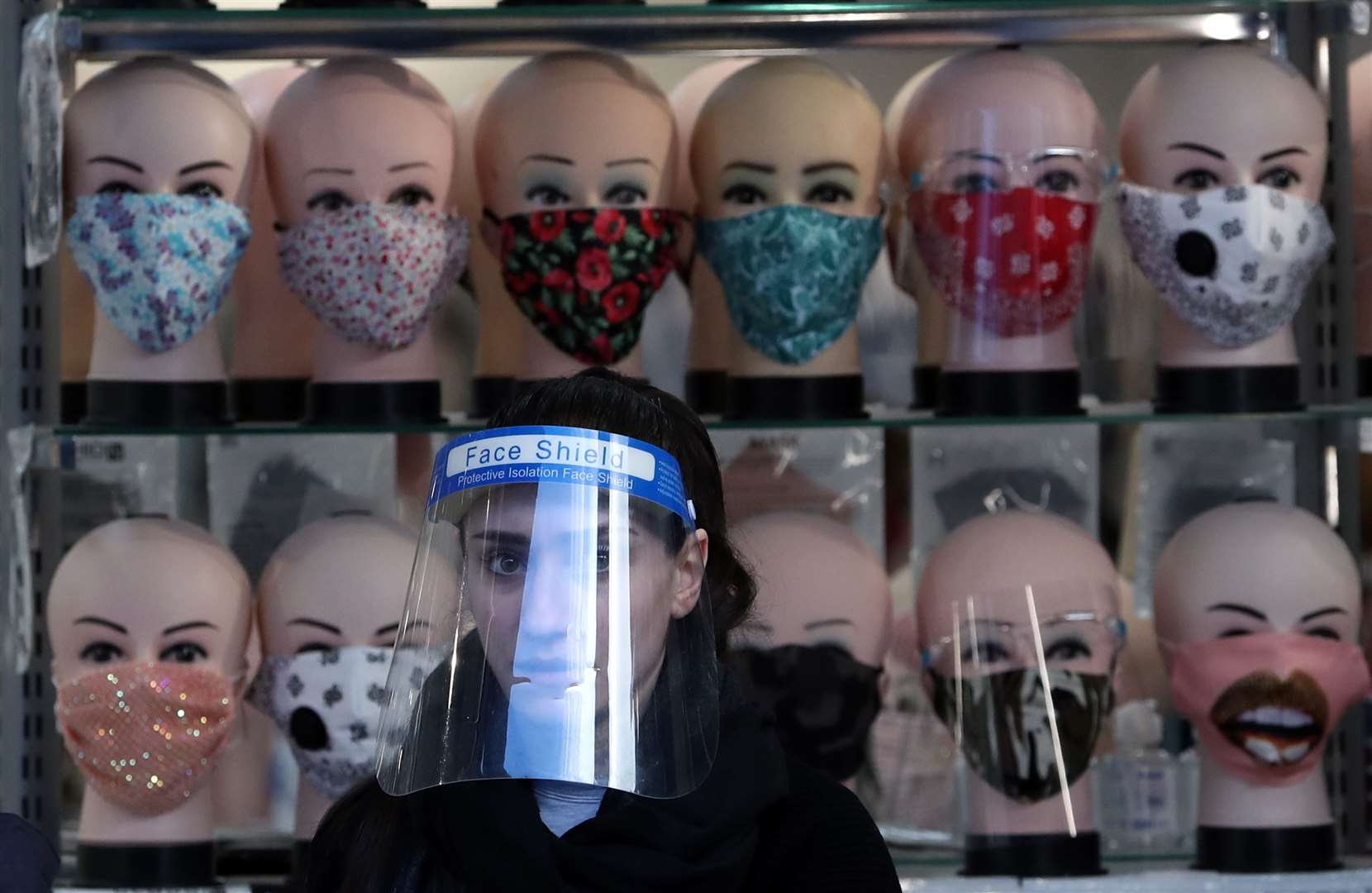 A sales assistant wearing a face covering helps customers at the entrance of a shop in Glasgow (Andrew Milligan/PA)