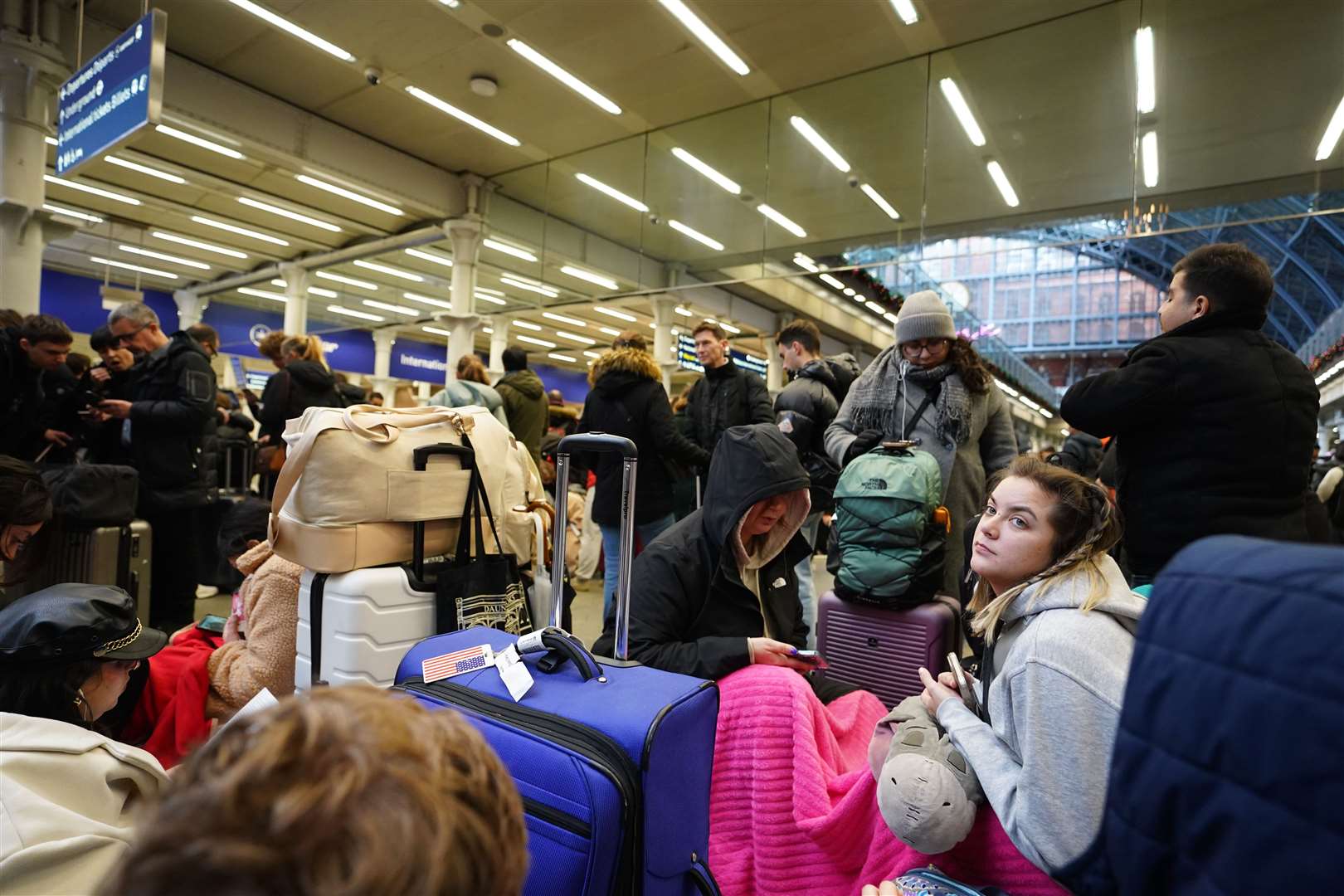 Passengers sit on the floor of the concourse at the entrance to Eurostar in St Pancras International station (James Manning/PA)