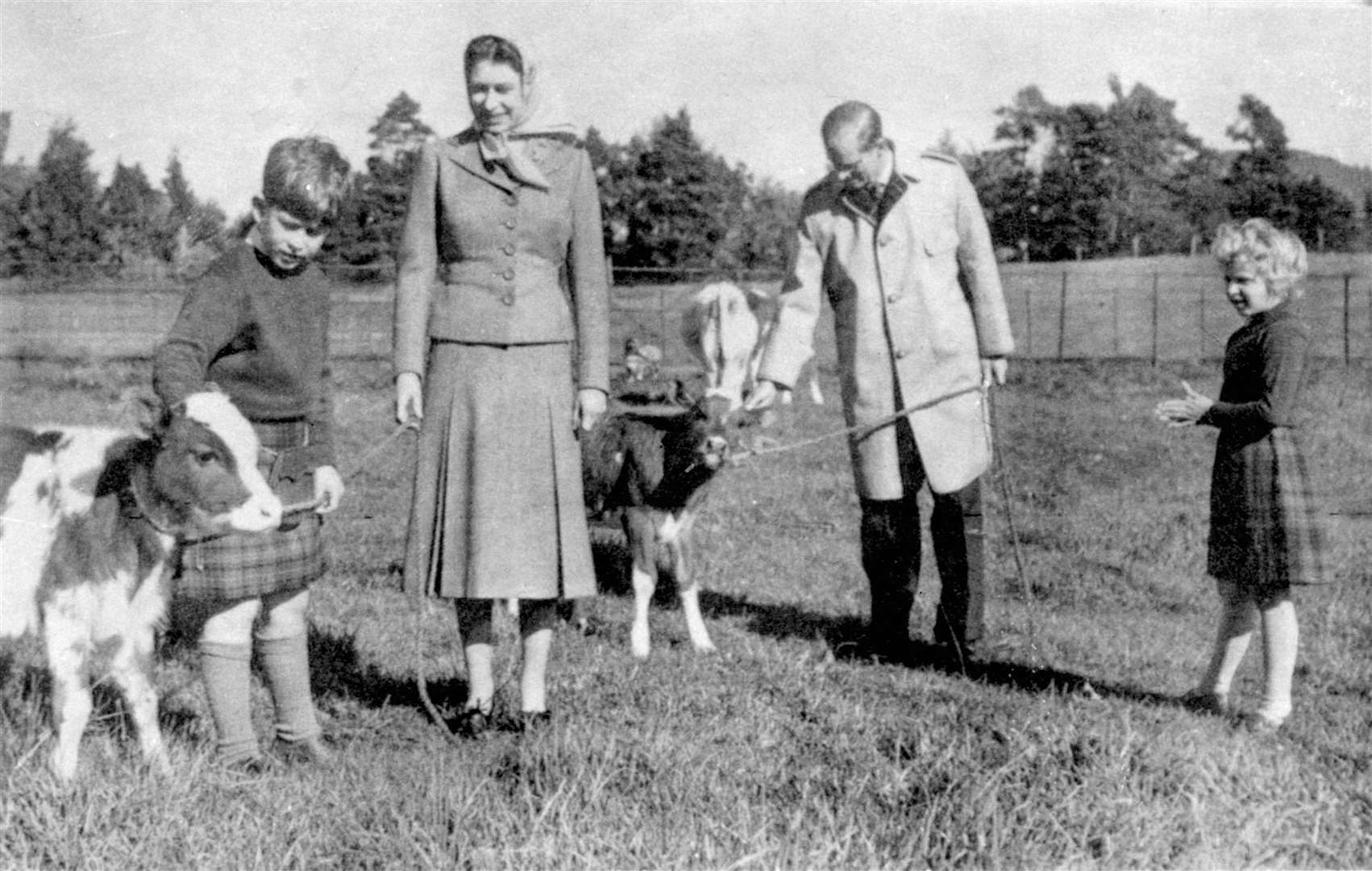 The Queen and Philip with a young Anne and Charles and Ayrshire calves on the Balmoral estate in 1957 (PA)