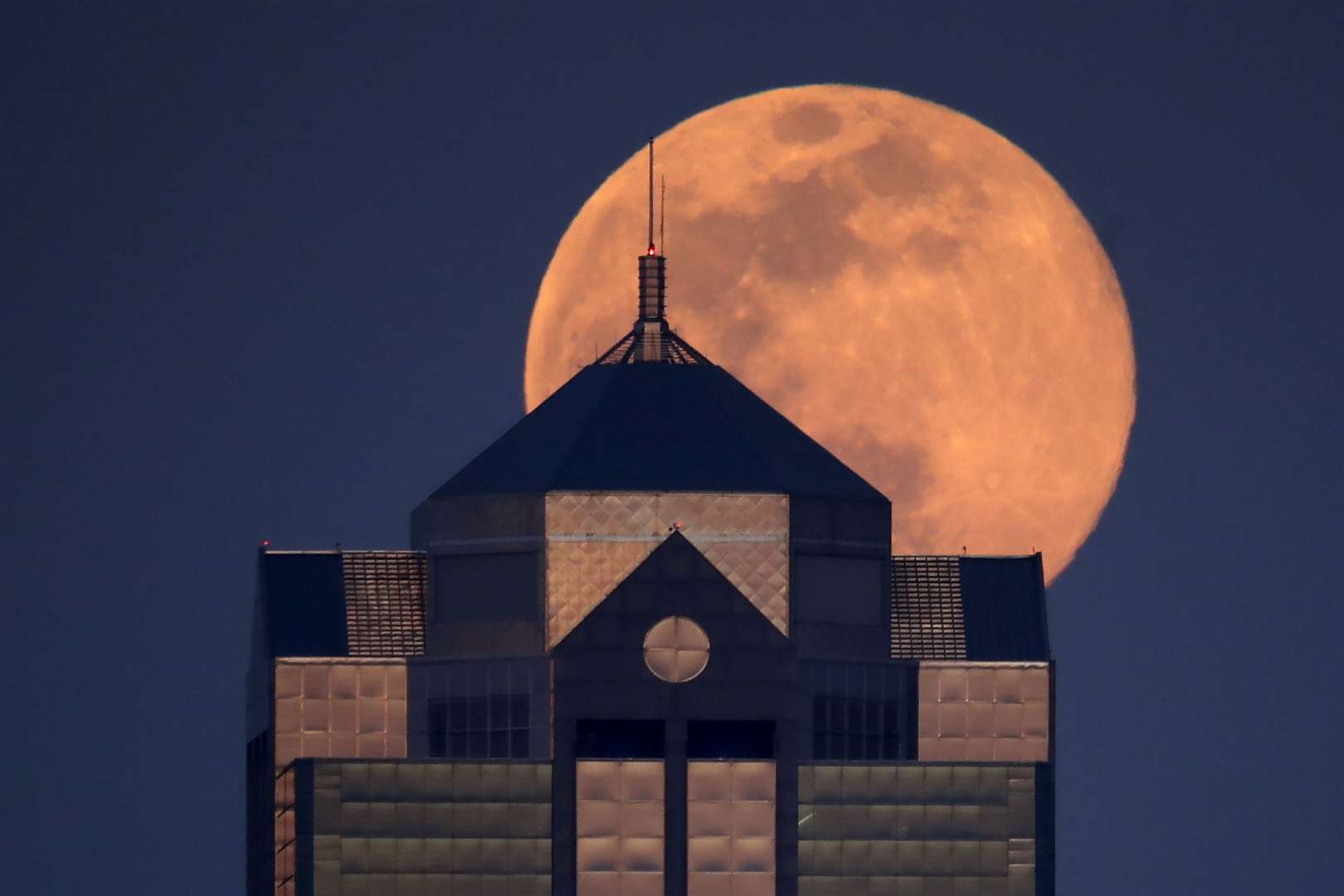 The supermoon rises behind an office building in Kansas City, Missouri (Charlie Riedel/AP)