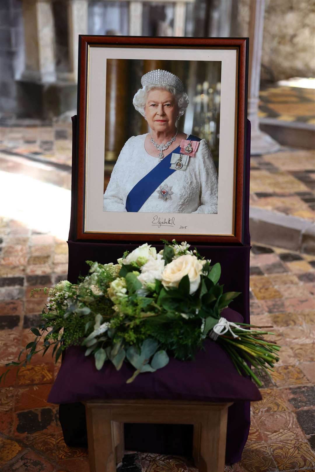 Flowers placed by the Prince and Princess of Wales are pictured next to a portrait of the late Queen during a service at St Davids Cathedral (Toby Melville/PA)