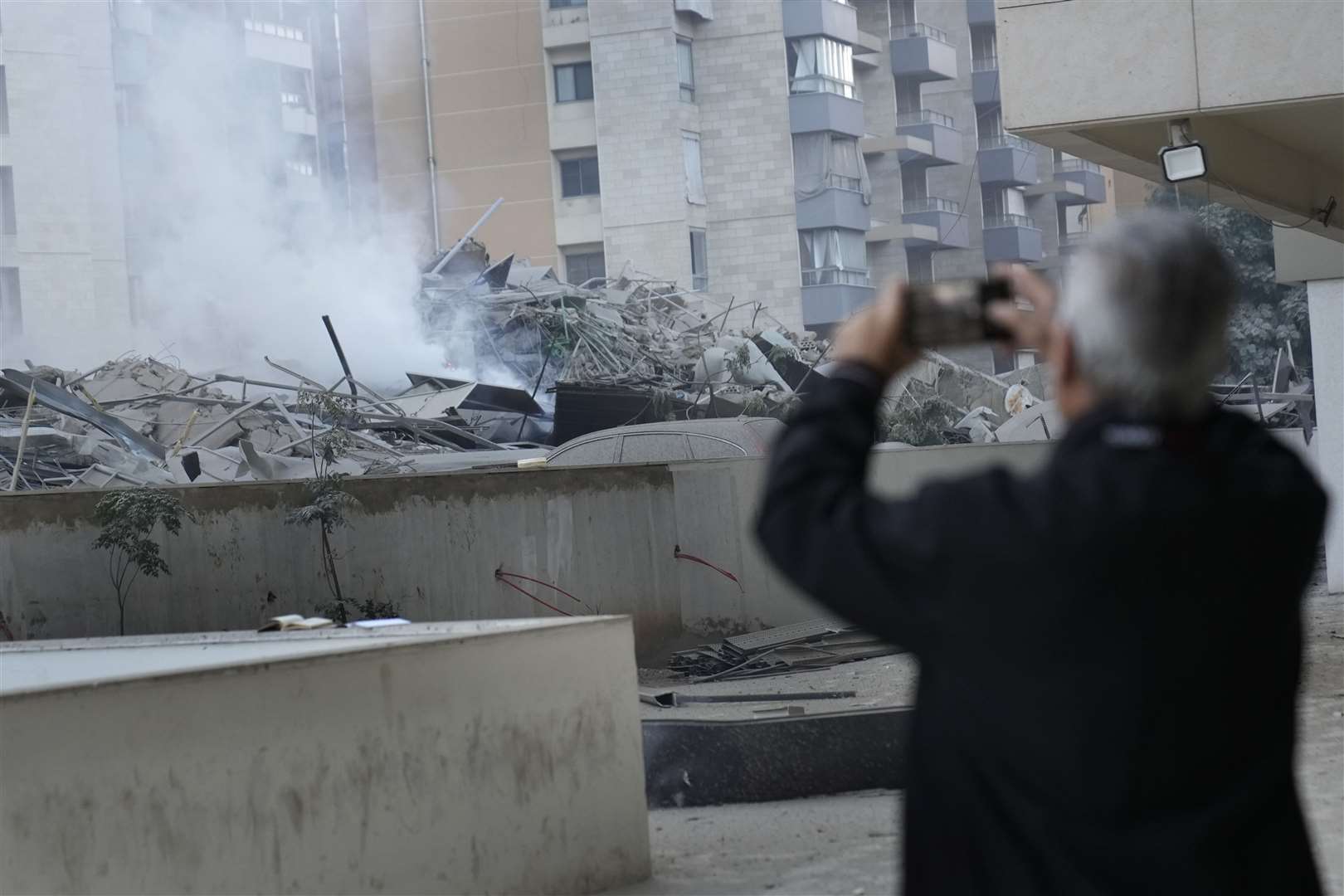 A man takes pictures of a residential complex hit by an Israeli airstrike in Dahieh, Beirut, Lebanon (Hussein Malla/AP)