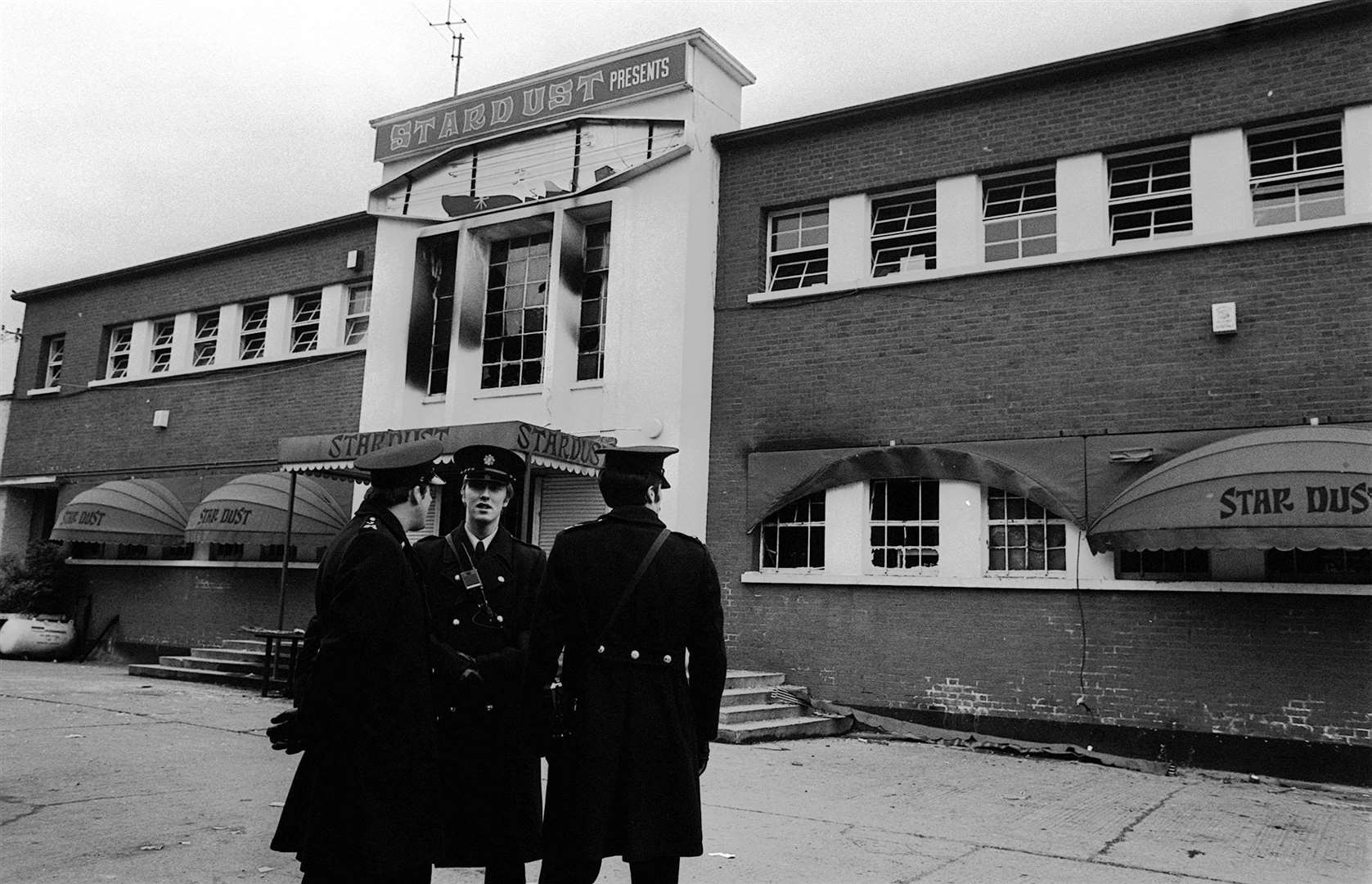 Police officers stand outside the main entrance to the fire-blackened Stardust Ballroom following the fire (Tony Harris/PA)