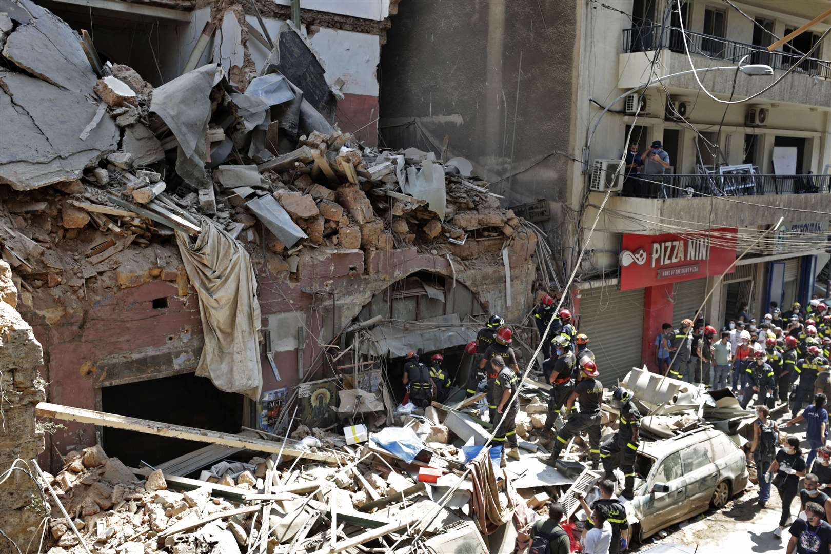 French and Lebanese firemen search in the rubble of a building (Hassan Ammar/AP)