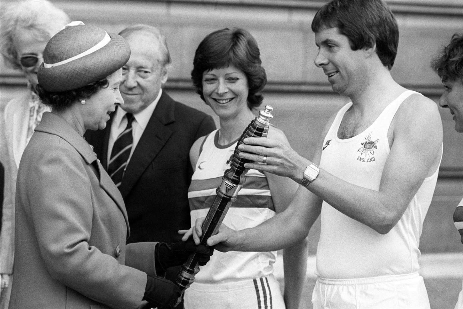 The Queen hands the baton for the Commonwealth Games relay to Brendan Foster (PA)