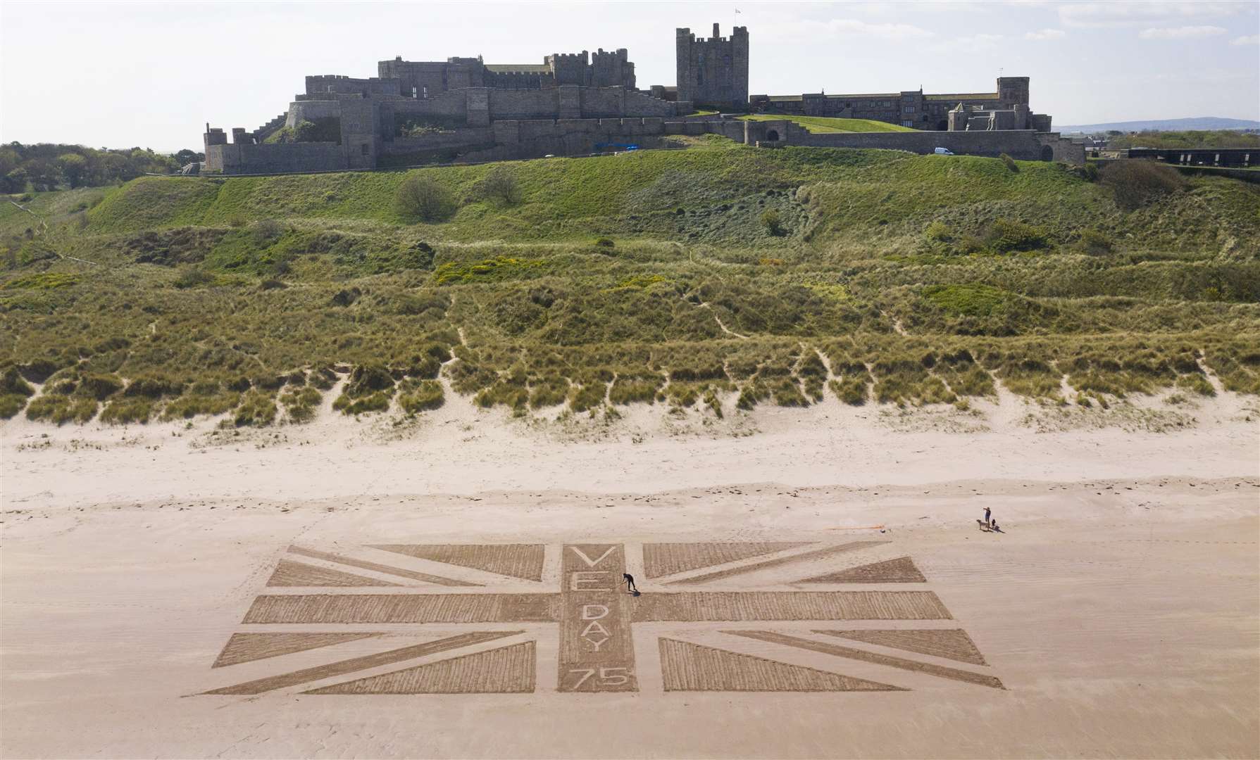 A giant Union flag was drawn in the sand on the beach beneath Bamburgh Castle in Northumberland by maintenance manager Andrew Heeley, 56 (Owen Humphreys/PA)