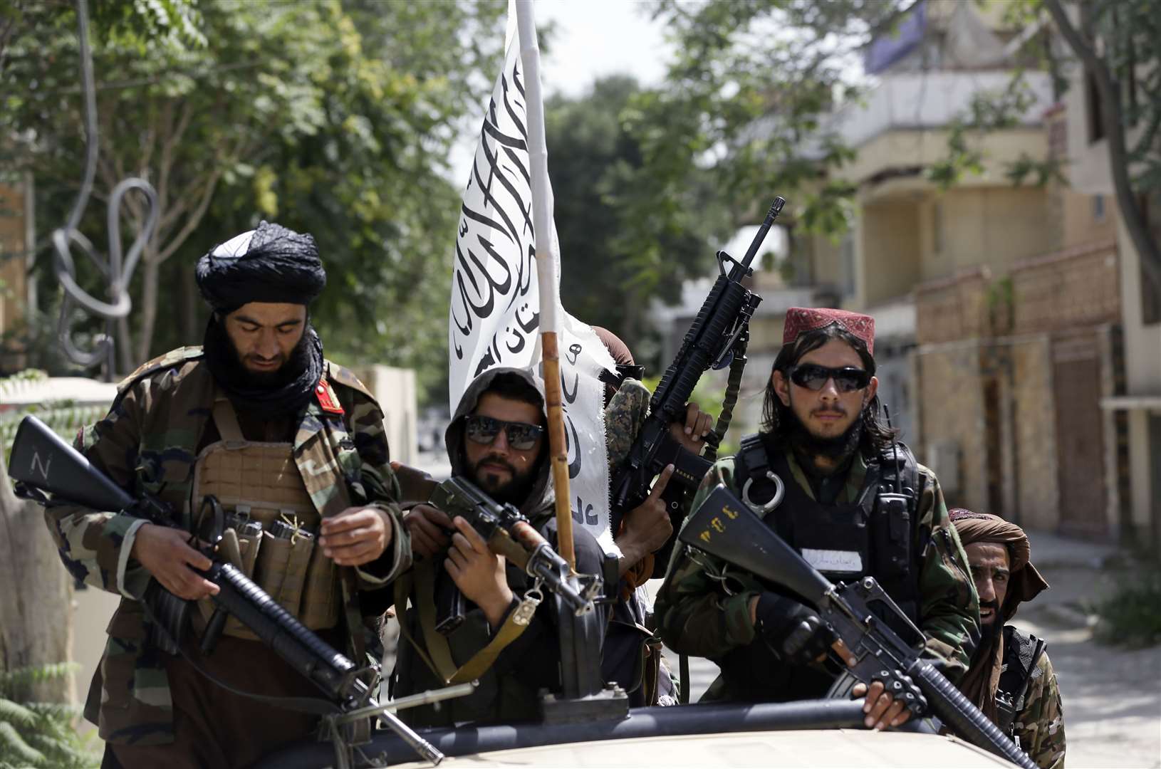 Taliban fighters display their flag on patrol in Kabul (Rahmat Gul/PA)