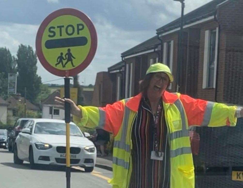 Lollipop lady Debbie Marsh dancing in the street at the end of a shift in Pottery Road, Hoo.