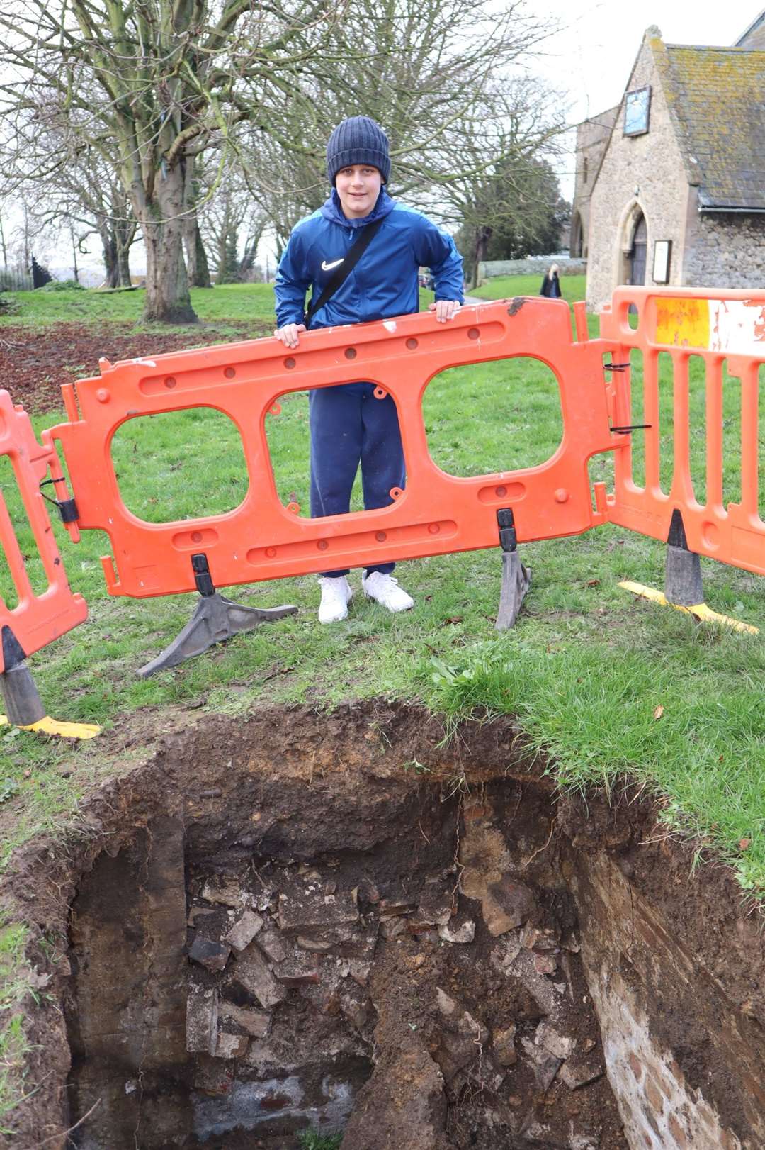 Brennen Spocchia, 13, studies a gaping hole has appeared in the graveyard of Minster Abbey on Sheppey. Could it be a long lost tunnel or an old tomb?