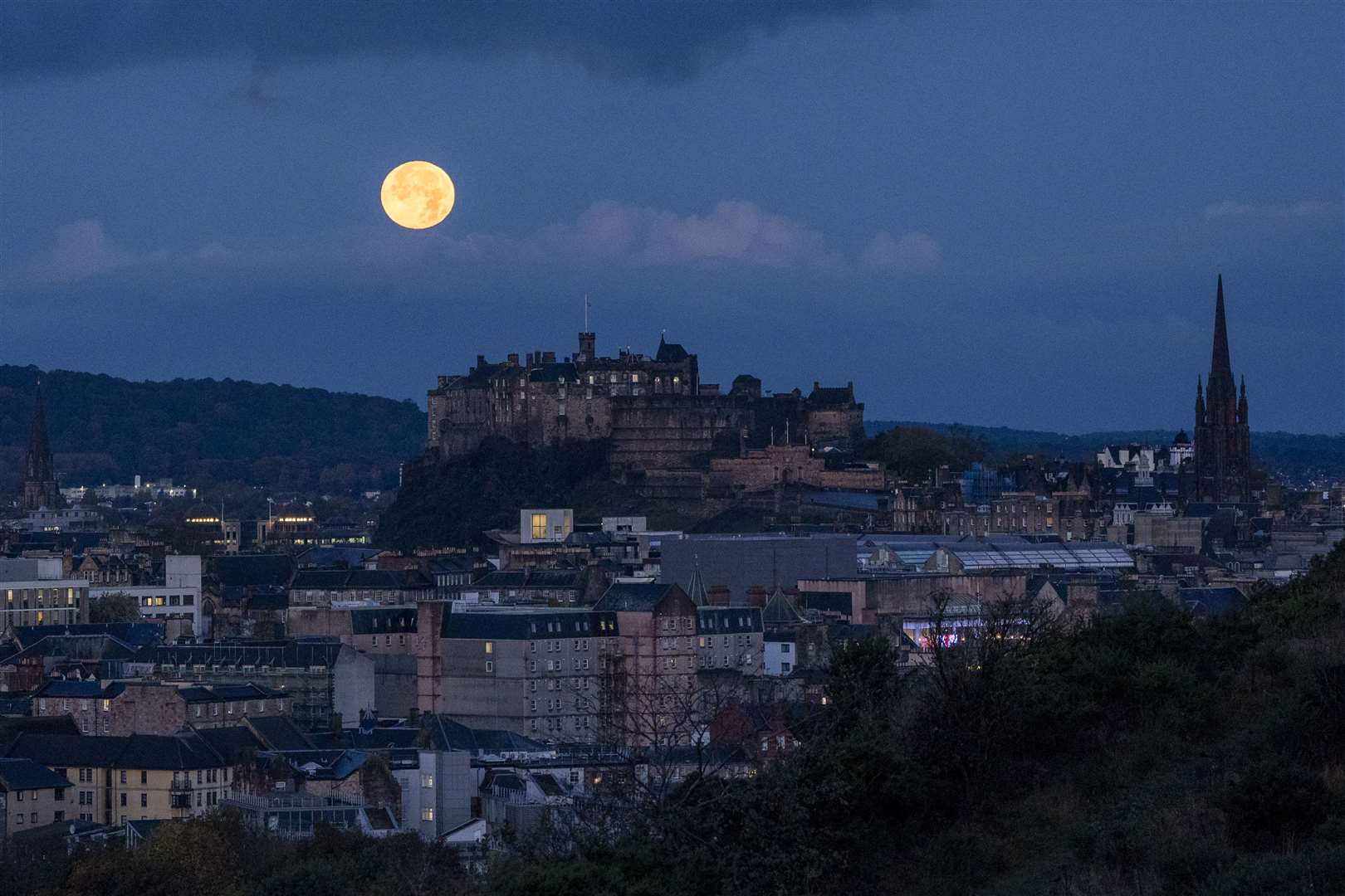 The full October moon, known as the Hunter’s, sets behind Edinburgh Castle (Jane Barlow/PA)