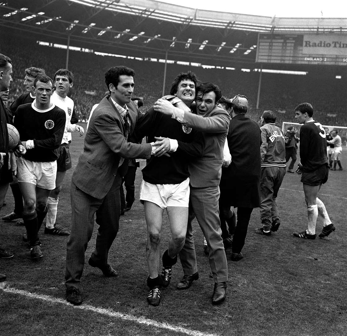 Jim Baxter is hugged by fans who invaded the pitch after Scotland’s famous 1967 victory at Wembley (PA)