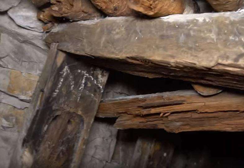 A rotting door frame holds up rocks. Mr Hallett makes his way down the cliff face. Picture: Abandoned World Explorer UK/YouTube