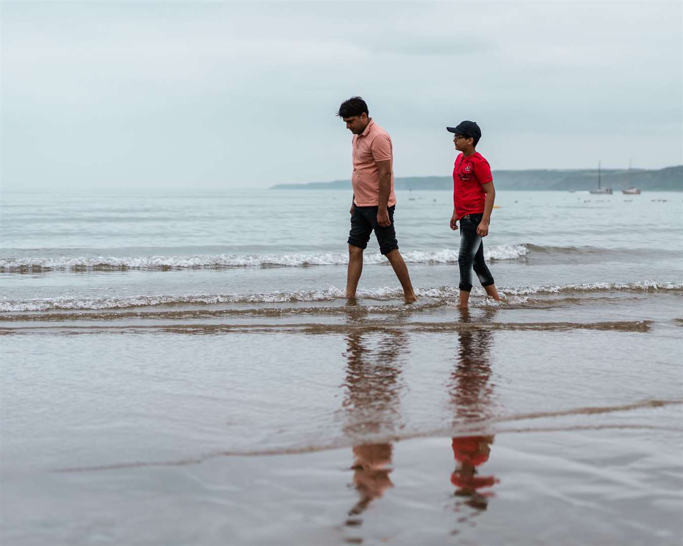 Ravi Saini, 10, from Leeds, and his father Nathu Ram, walk in the sea (Erik Woolcott/PA)