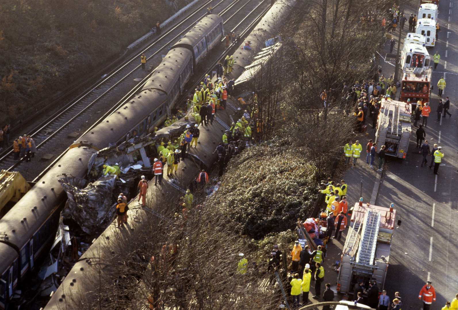 Rescue workers clamber over the wreckage of three trains that crashed near Clapham Junction in December 1988 (PA)