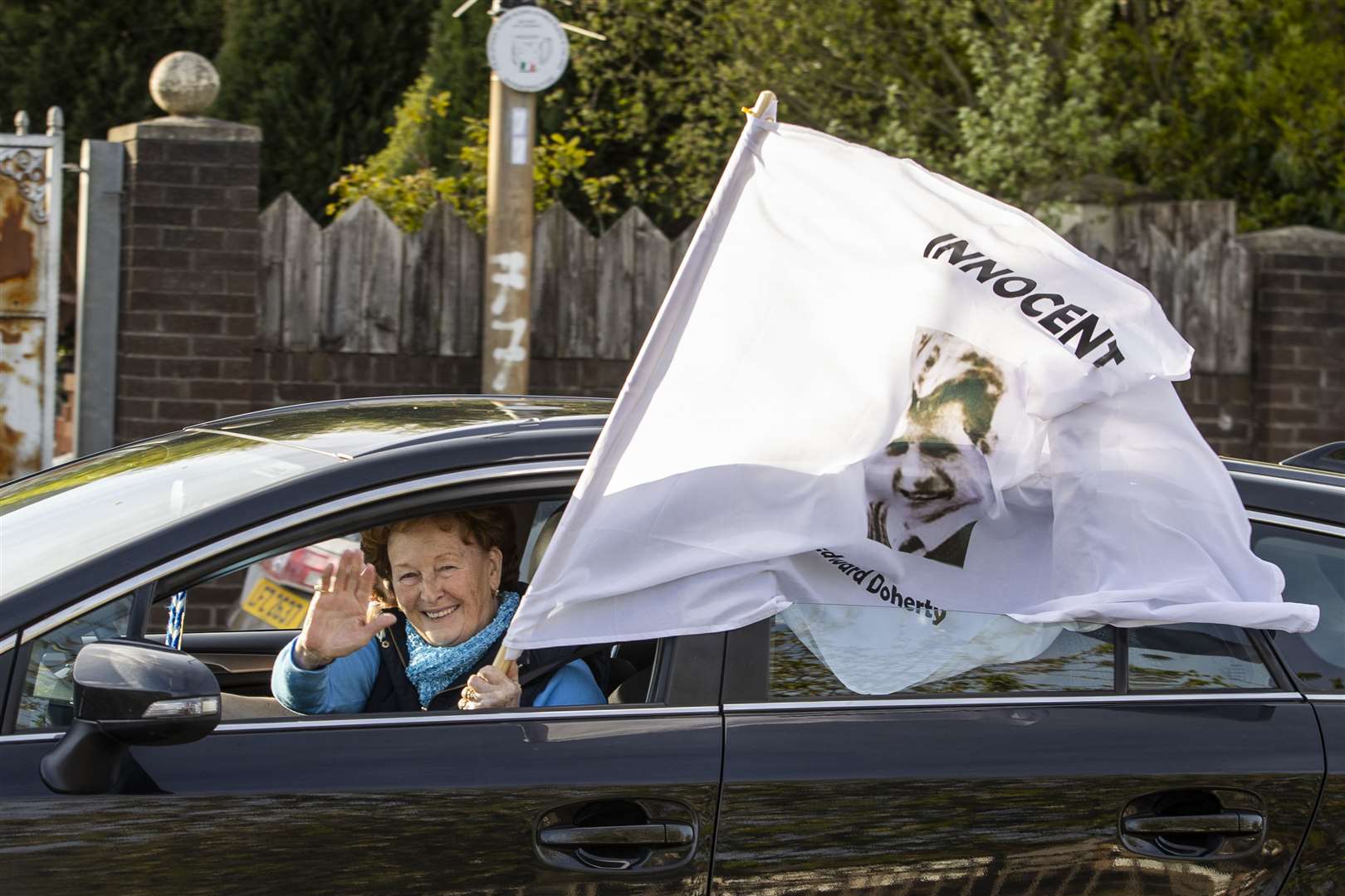One of the cavalcade with a white flag bearing victim, Edward Doherty’s picture and the word ‘innocent’ (Liam McBurney/PA)