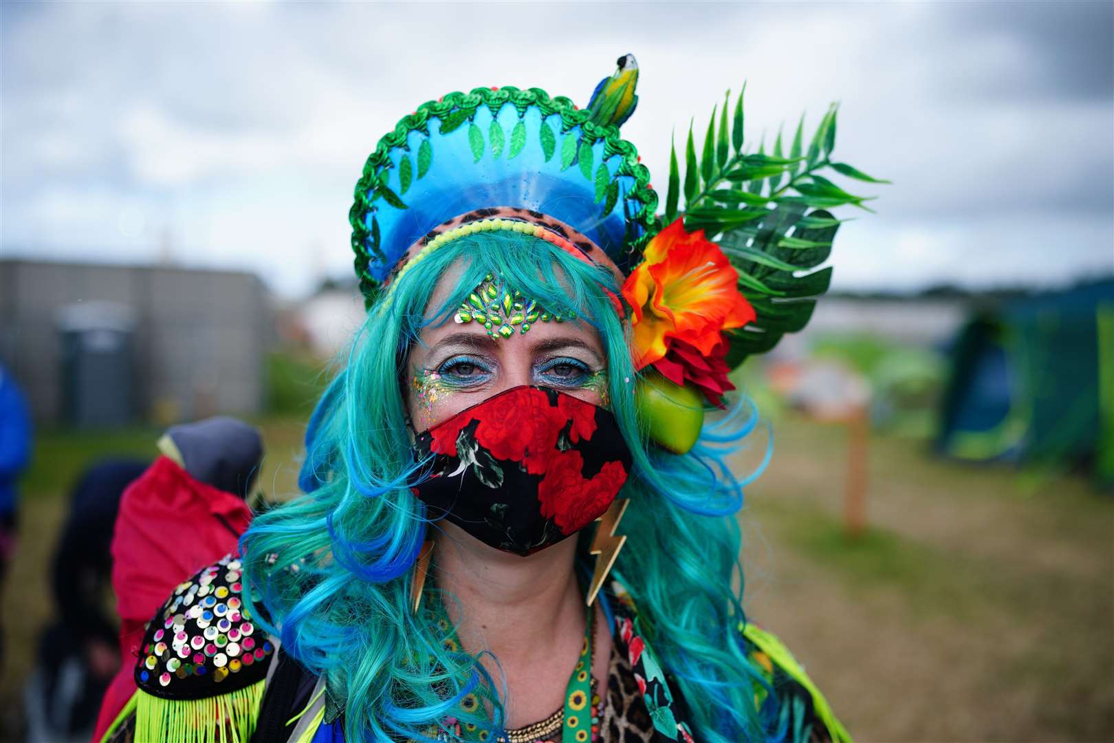 A festival-goer wearing a face mask as part of their elaborate outfit (Ben Birchall/PA)