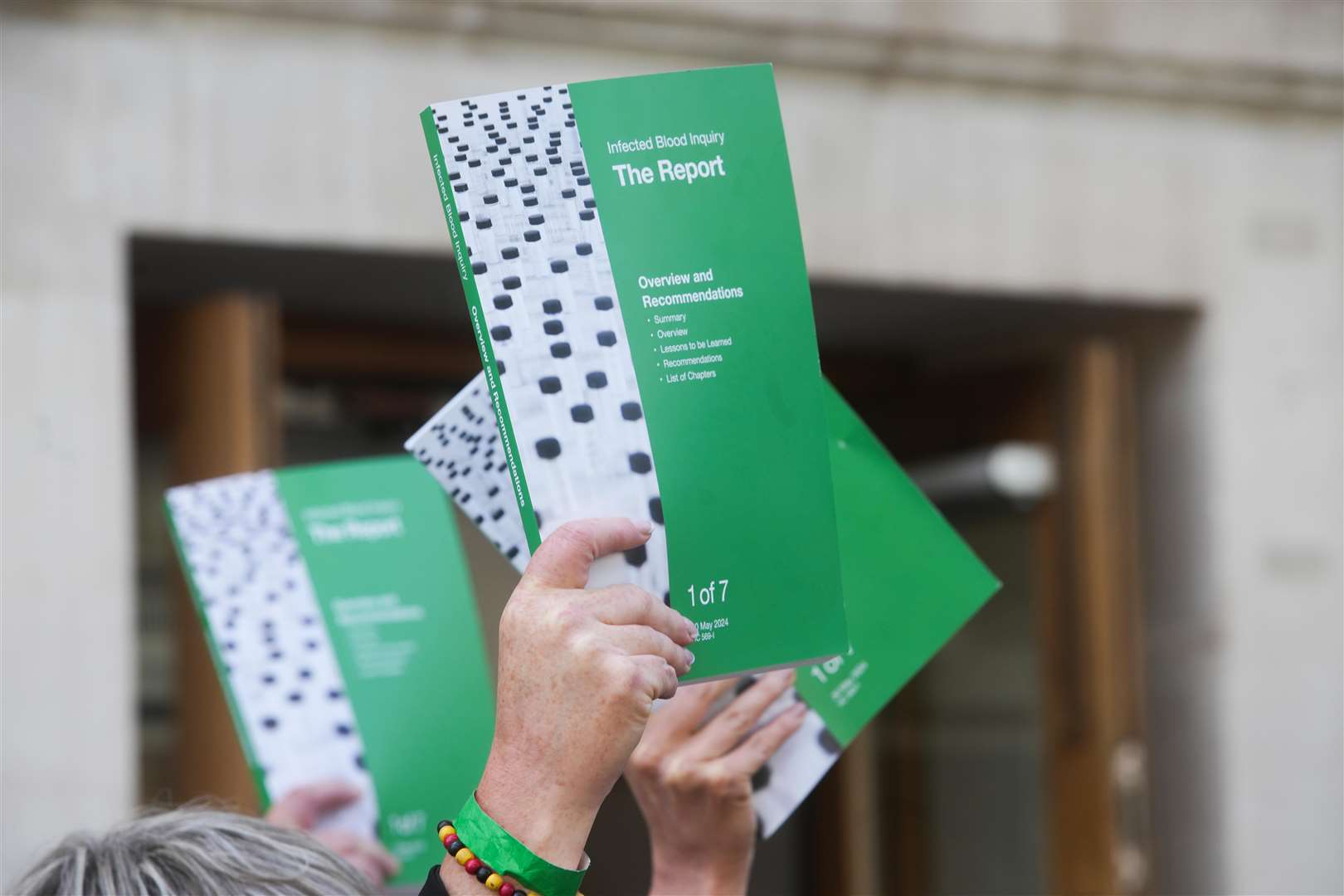 People holding up copies of the Infected Blood Inquiry report (Jeff Moore/PA)