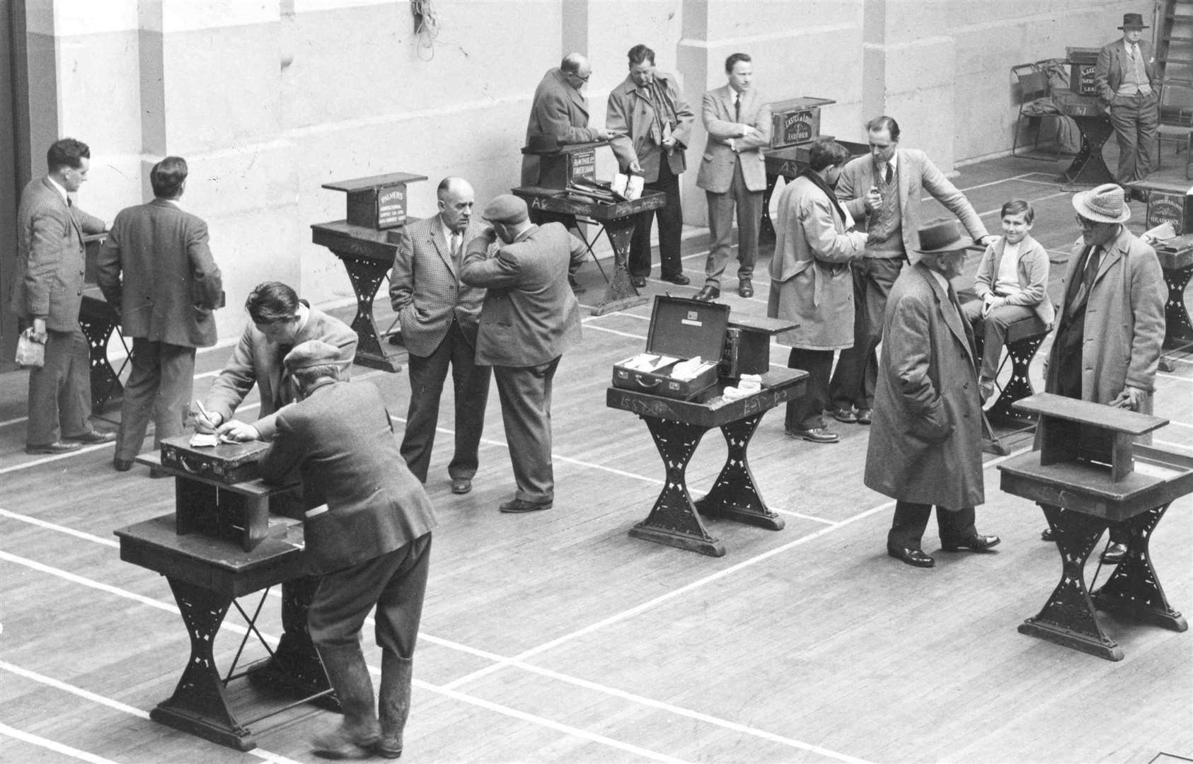 Inside the old corn exchange in Ashford, traders discuss seek deals in this 1963 picture. The building was demolished and replaced by an office block for the Commercial Union Assurance and shops on the corner of Bank Street and Elwick Road. Picture: Images of Ashford by Mike Bennett