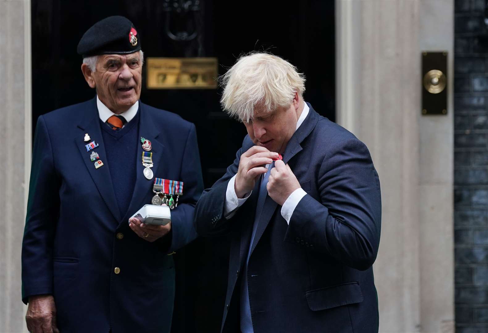 Boris Johnson attaches his poppy after purchasing it from fundraisers (Steve Parsons/PA)