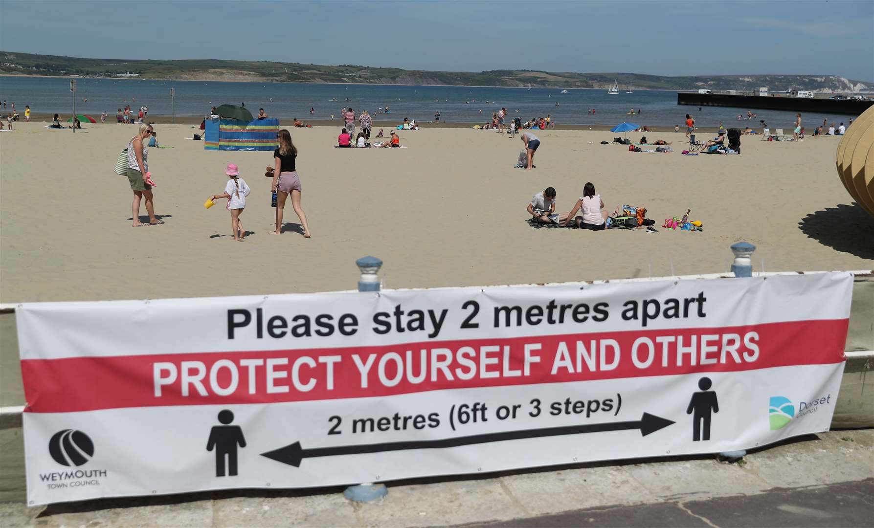 People on Weymouth beach in Dorset are reminded about social distancing (Andrew Matthews/PA)