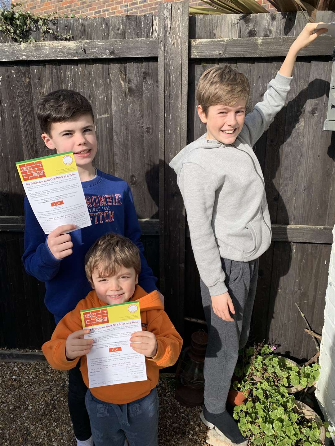 Jack Bridges, Charlie Rutter and Stanley Bridges delivering leaflets to encourage people to buy a brick