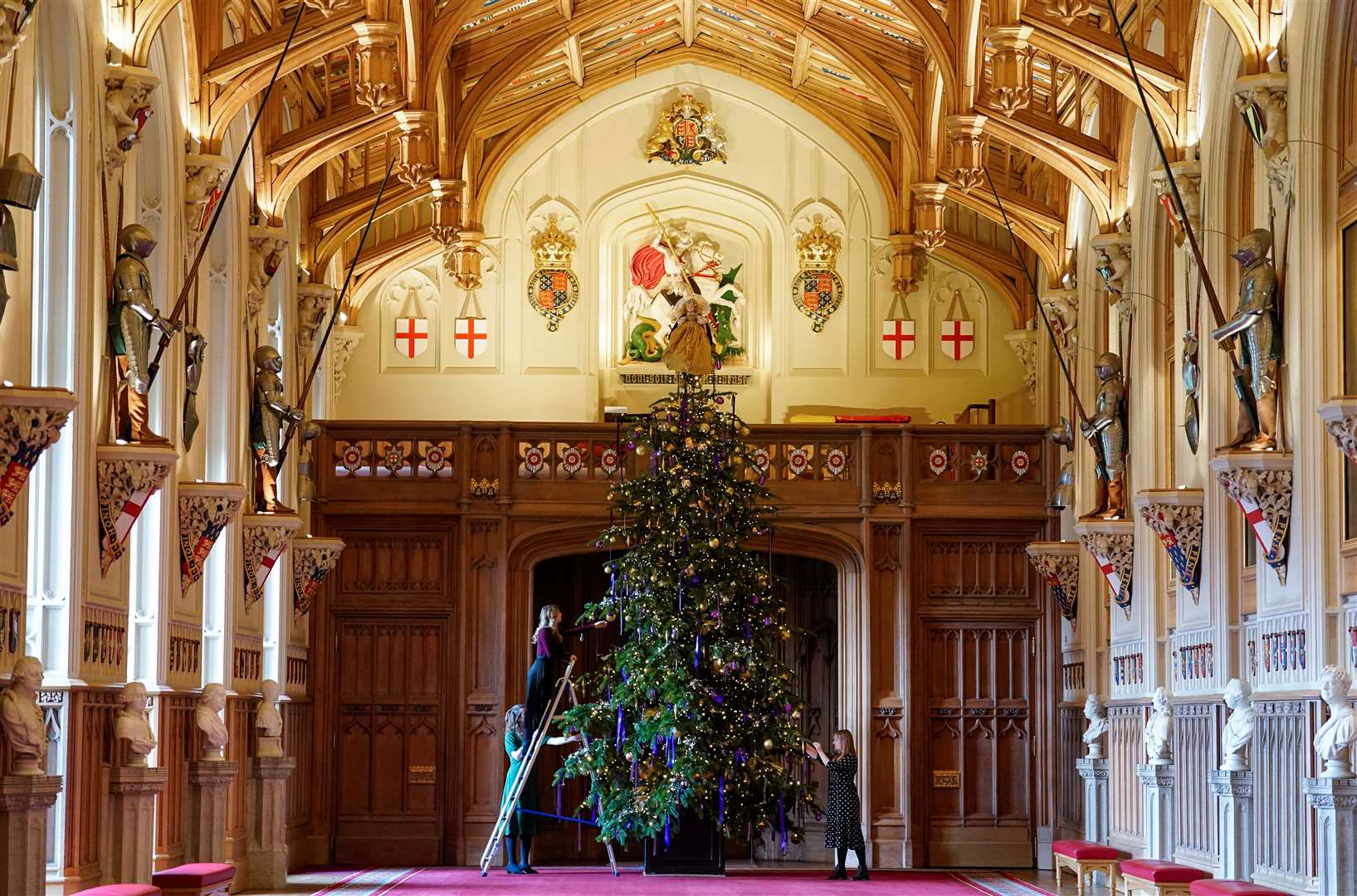 Staff at the Royal Collection Trust make finishing touches to a 20ft Nordmann fir Christmas tree in St George’s Hall (Andrew Matthews/PA)